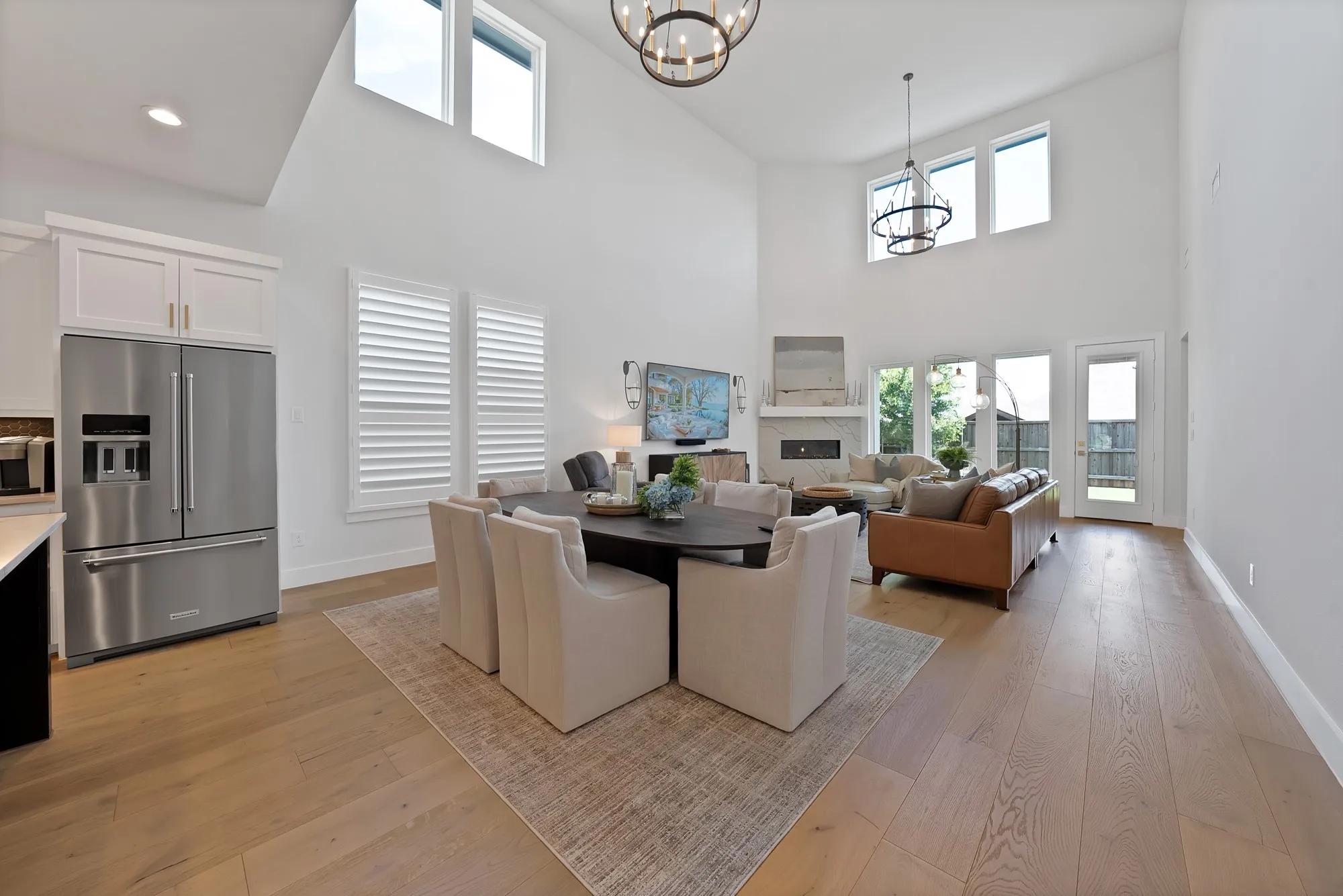 Spacious open-concept living area featuring a two-story ceiling, light wood-finish flooring, and multiple windows