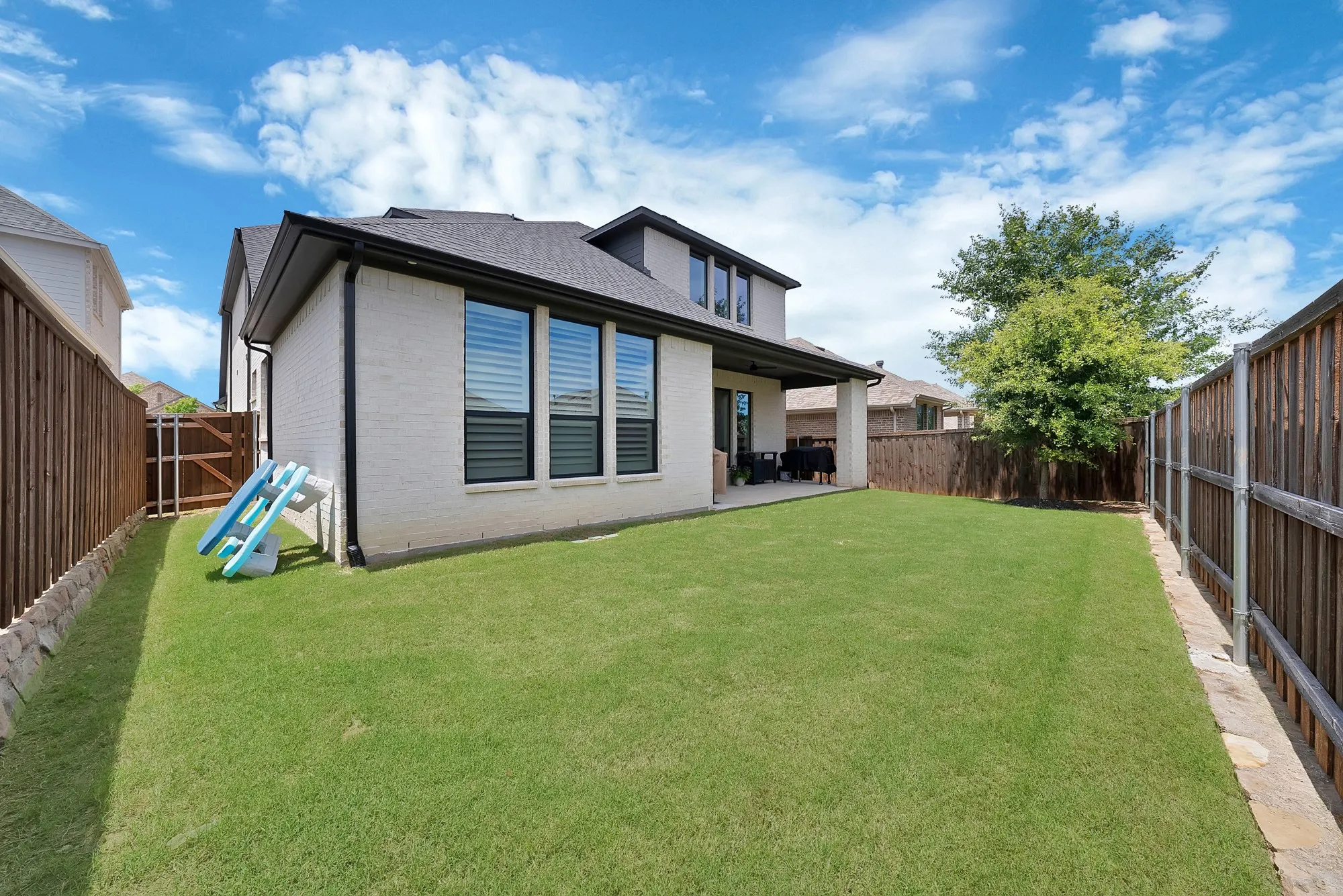 Spacious backyard featuring a lush lawn and perimeter wood fencing