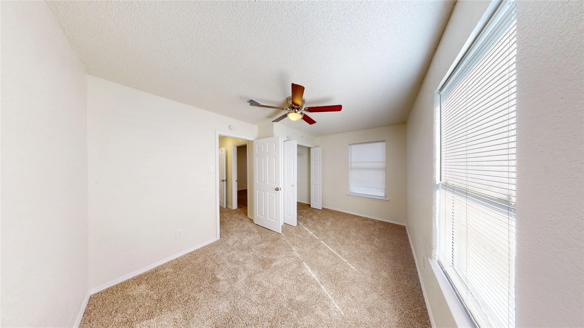 Unfurnished bedroom with light carpet, ceiling fan, a textured ceiling, and a closet