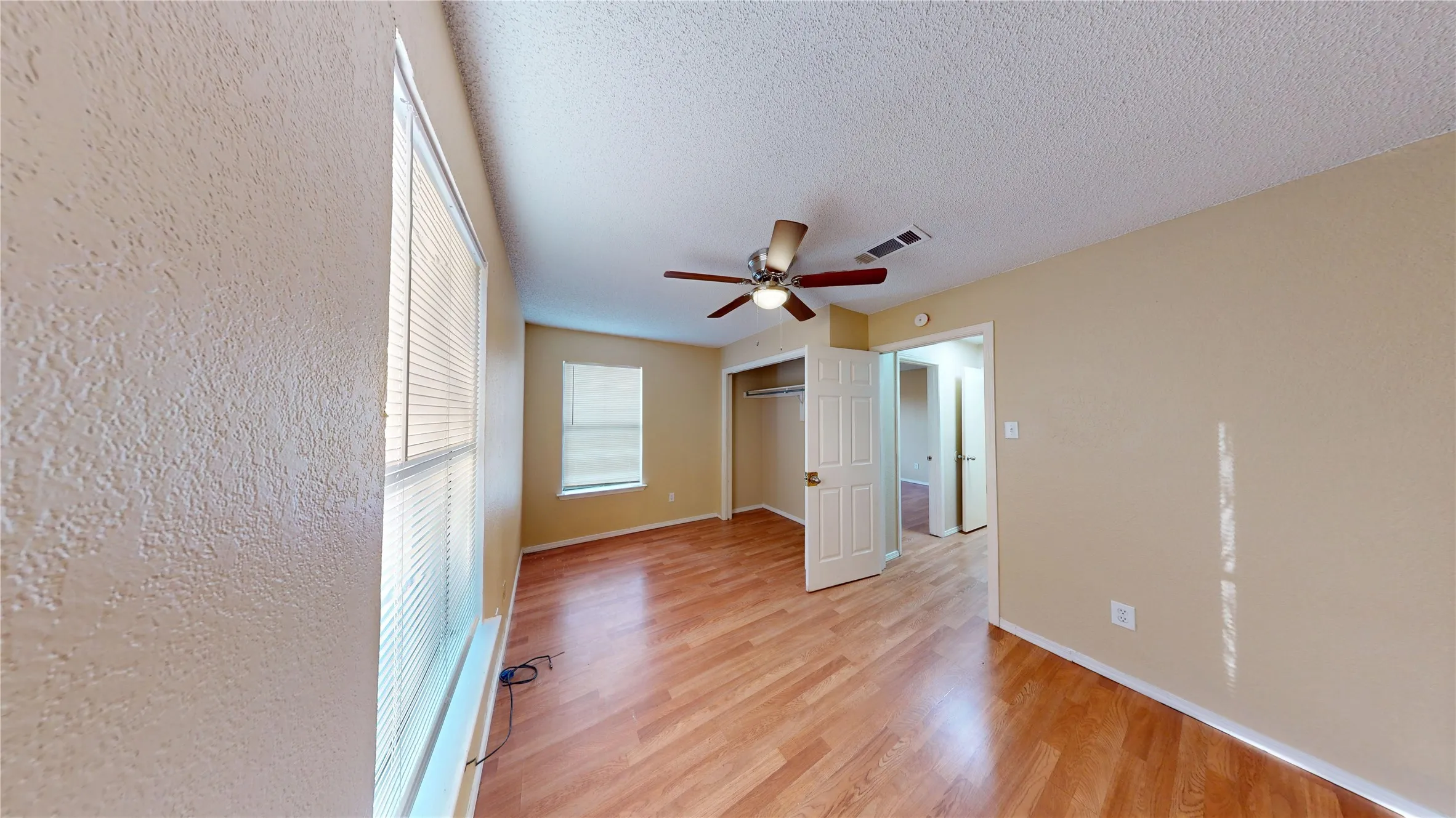 Unfurnished room with light wood-style flooring, a textured ceiling, and a ceiling fan