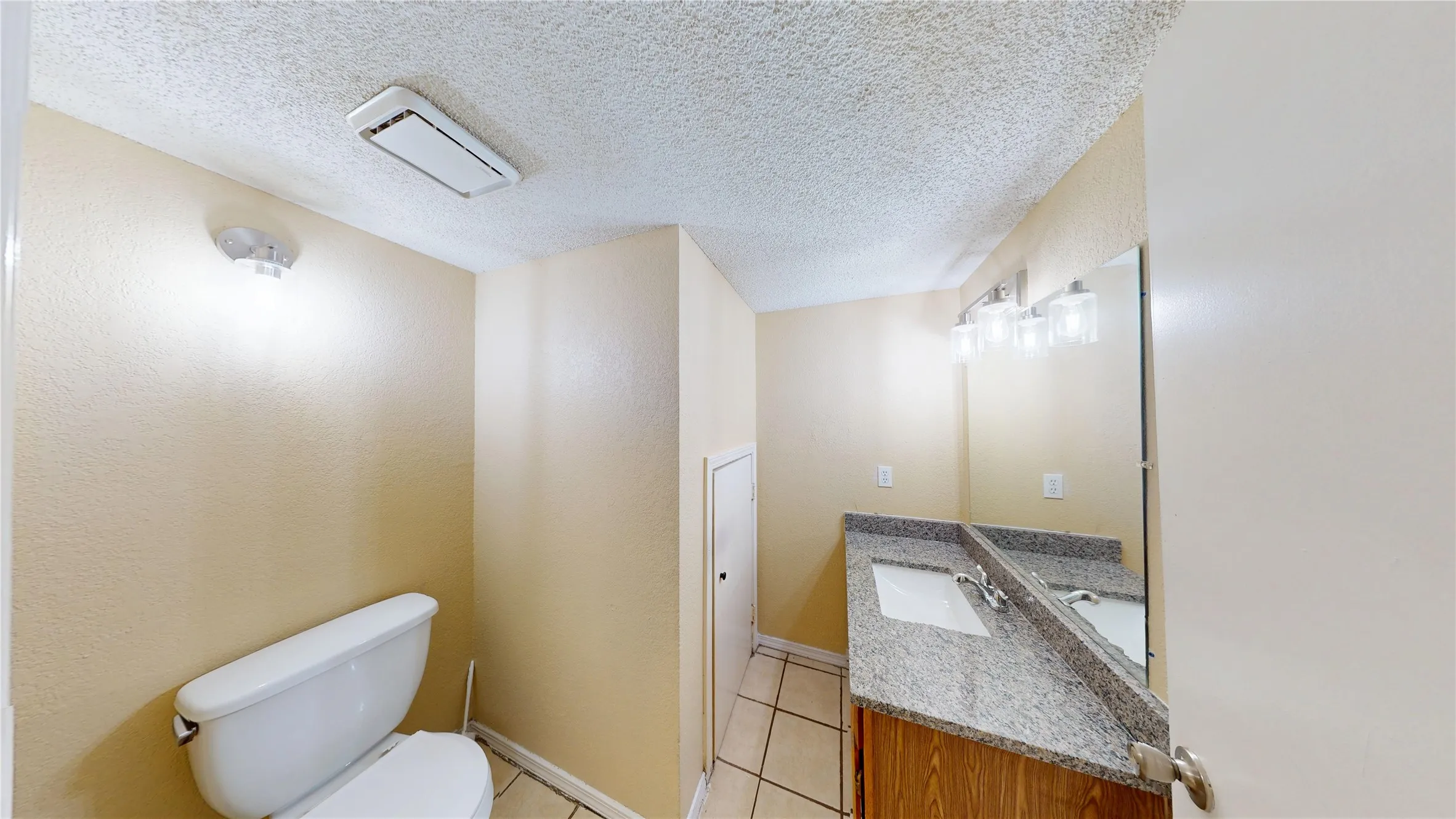 Half bathroom featuring vanity, light tile patterned floors, and a textured ceiling