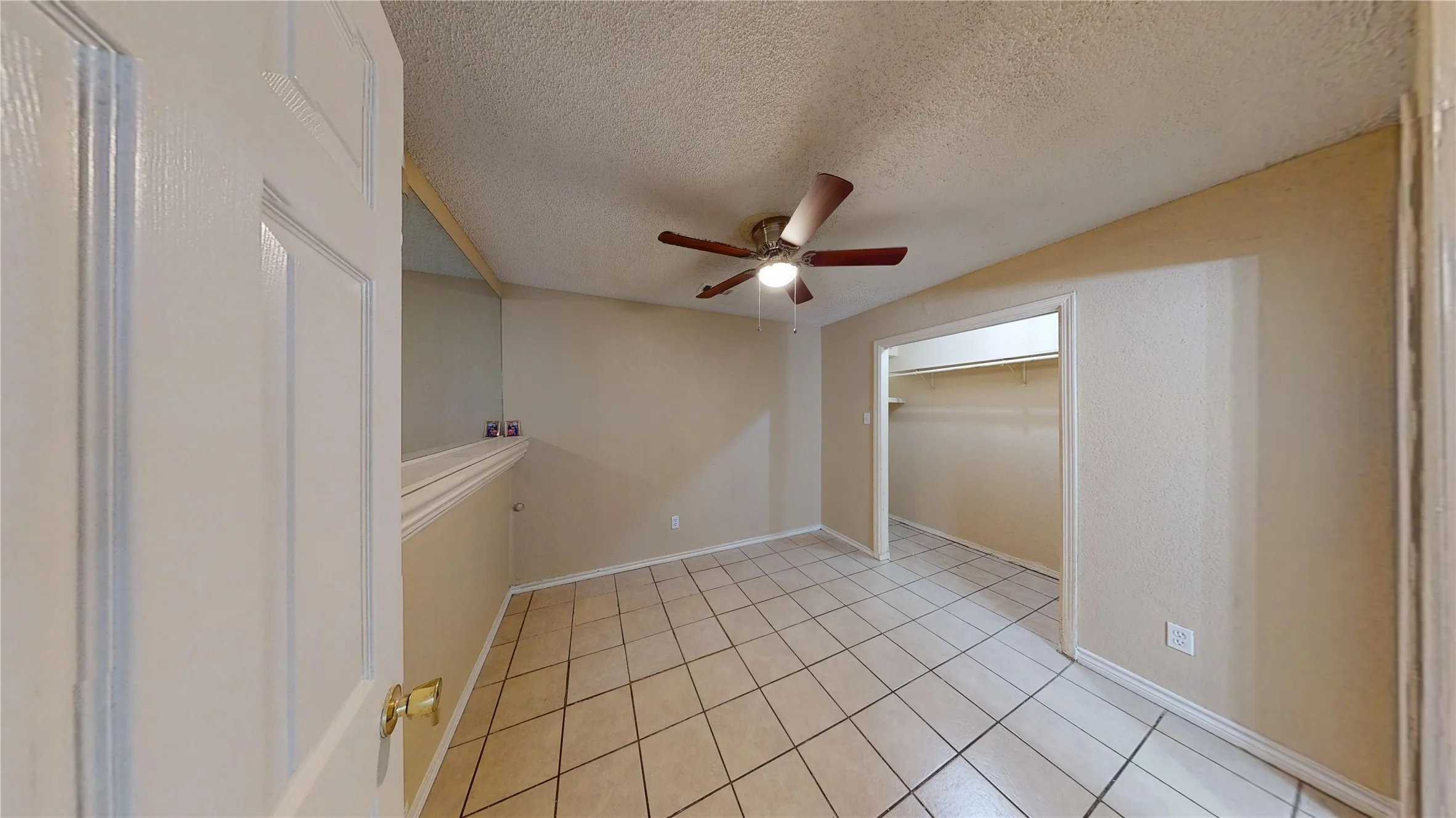 Unfurnished room with a textured ceiling, a ceiling fan, and light tile patterned floors