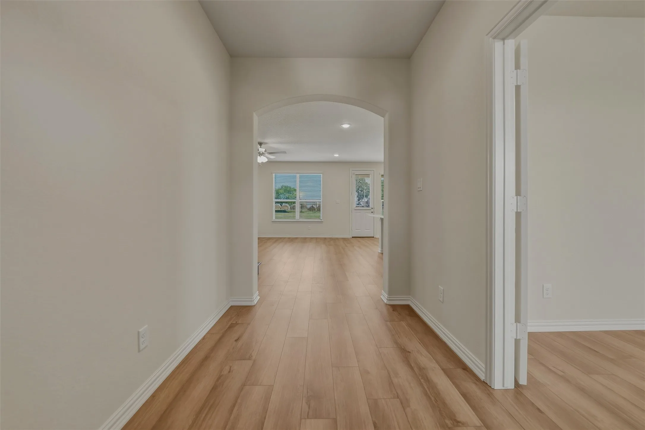 Arched entryway featuring wood-finish flooring and neutral wall tones