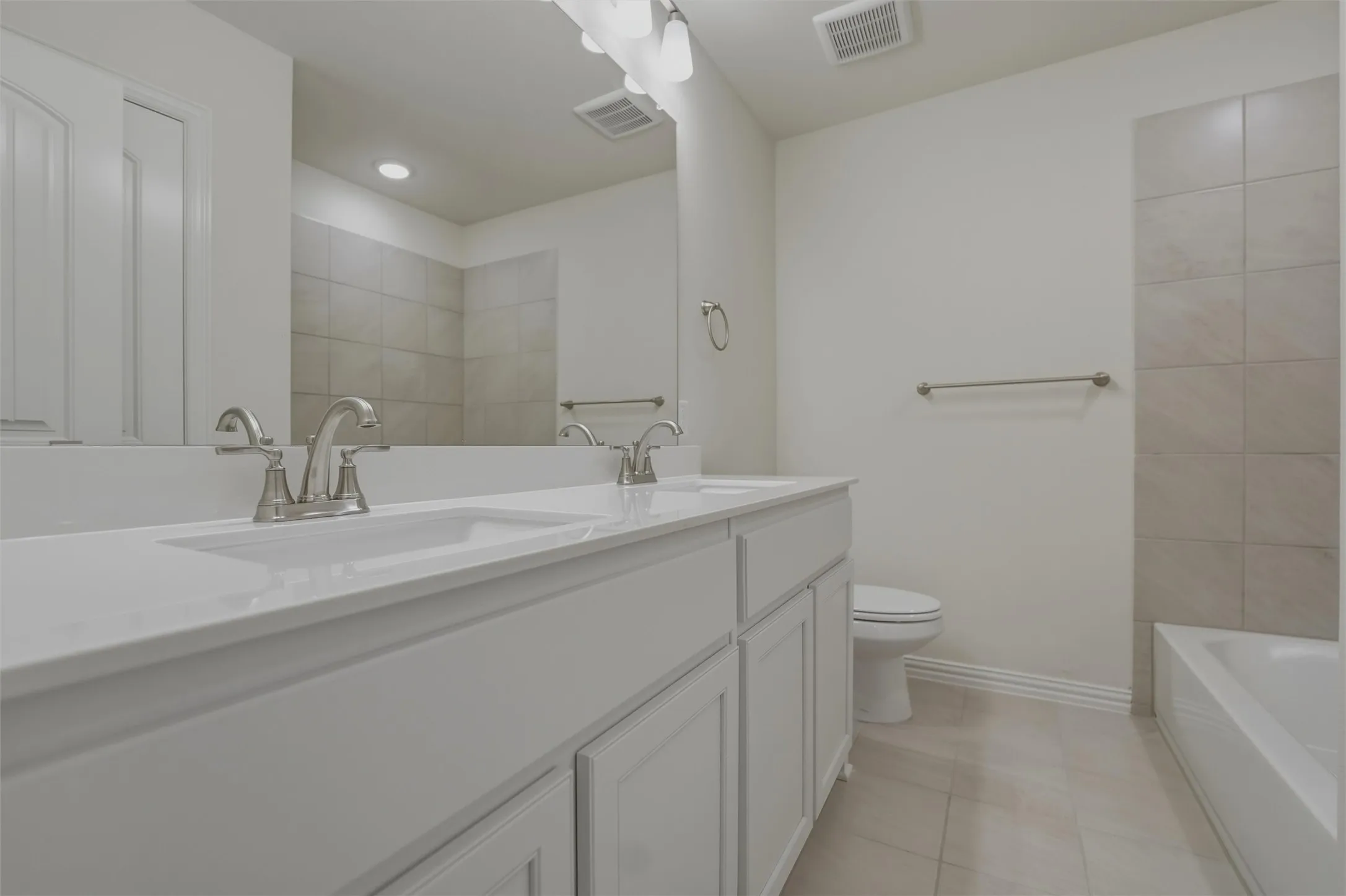 Spa-inspired primary bathroom featuring a dual-sink vanity with white cabinetry, quartz countertop, and brushed nickel faucets