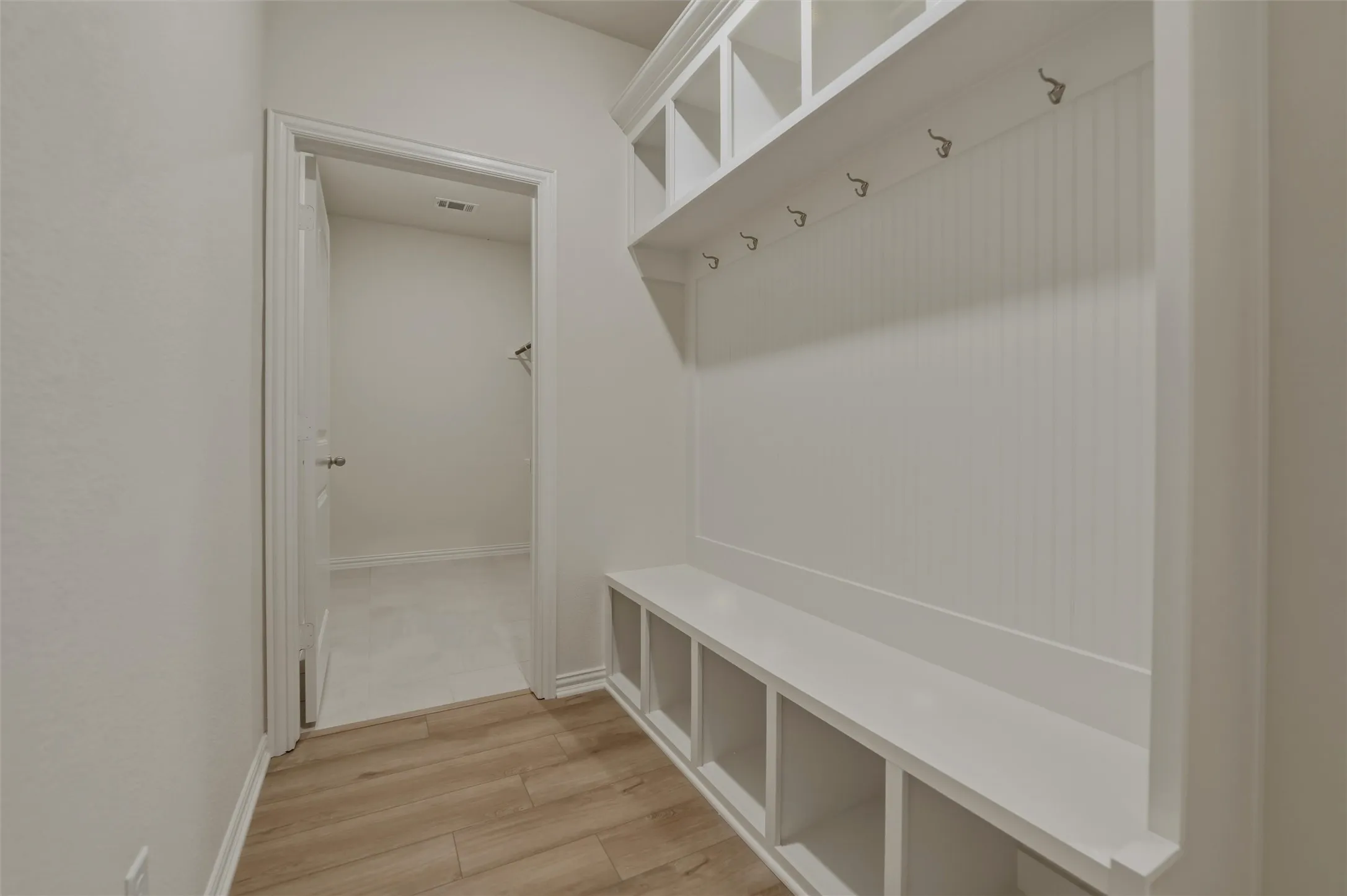 Built-in storage bench with cubbies, upper shelving, and coat hooks