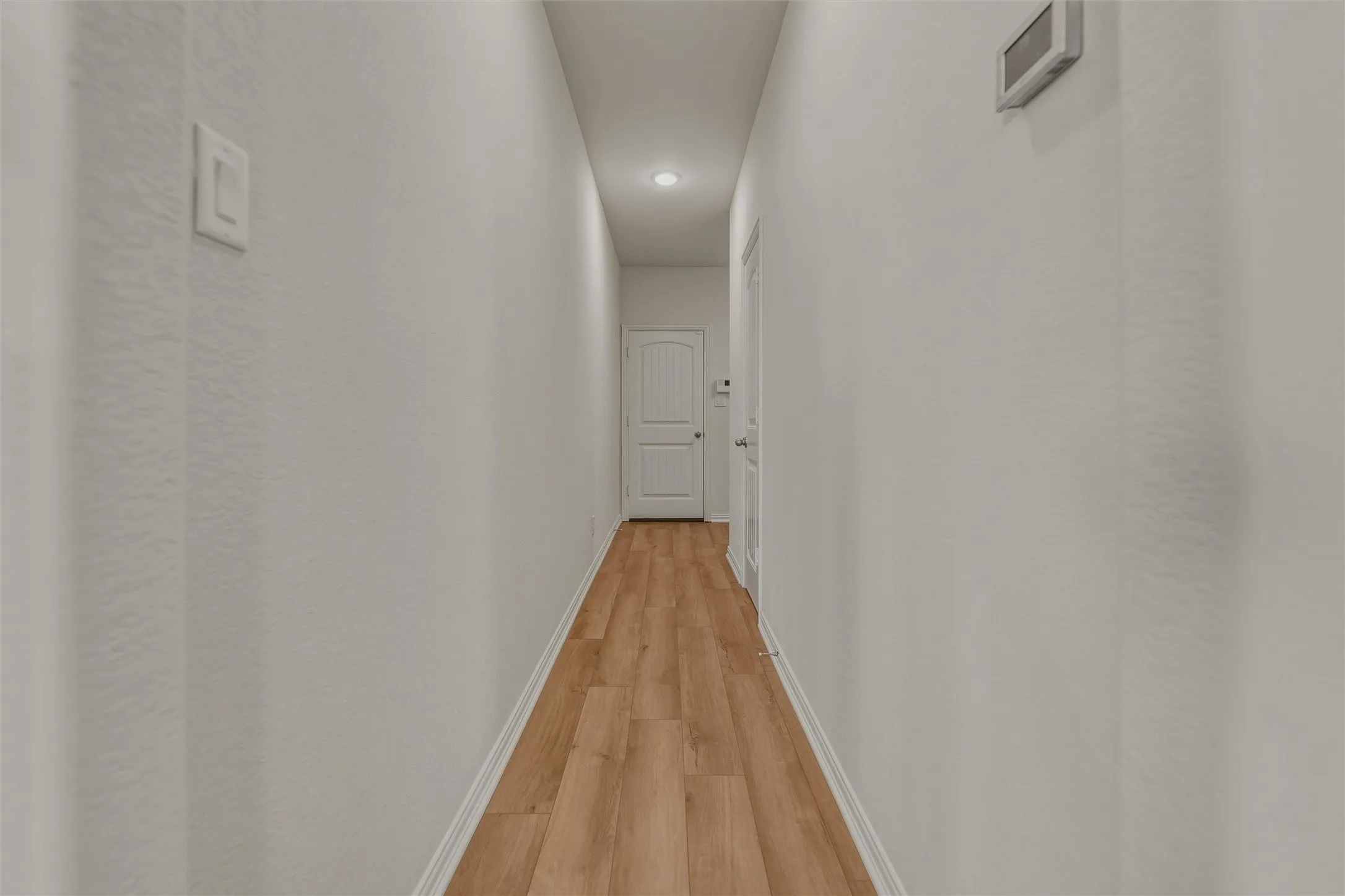 Recessed ceiling lighting, wood-finish flooring, and white interior doors