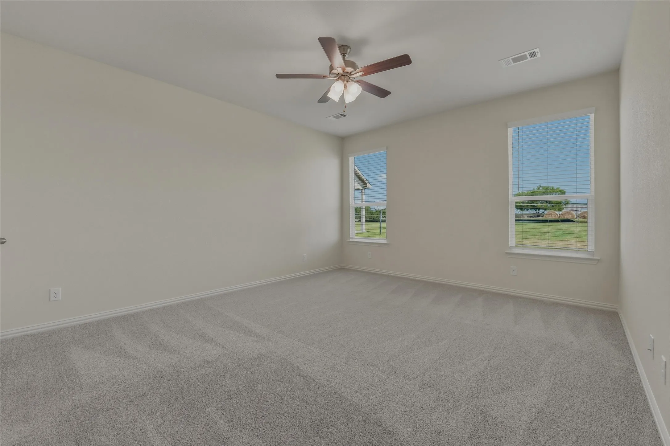 Spacious room featuring light gray carpeting and neutral wall tones