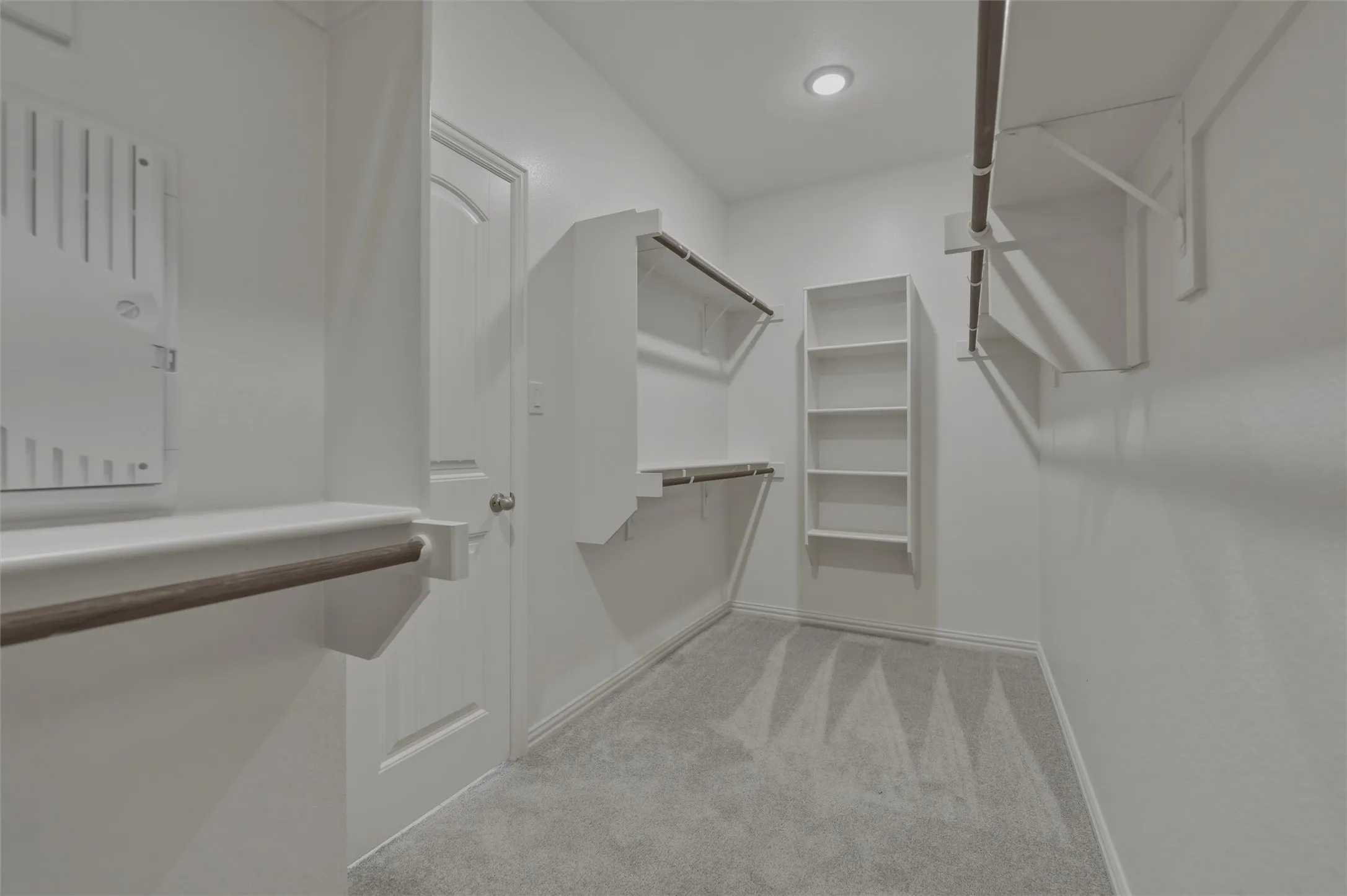 White interior walls with recessed lighting, light gray carpet, and white built-in shelving