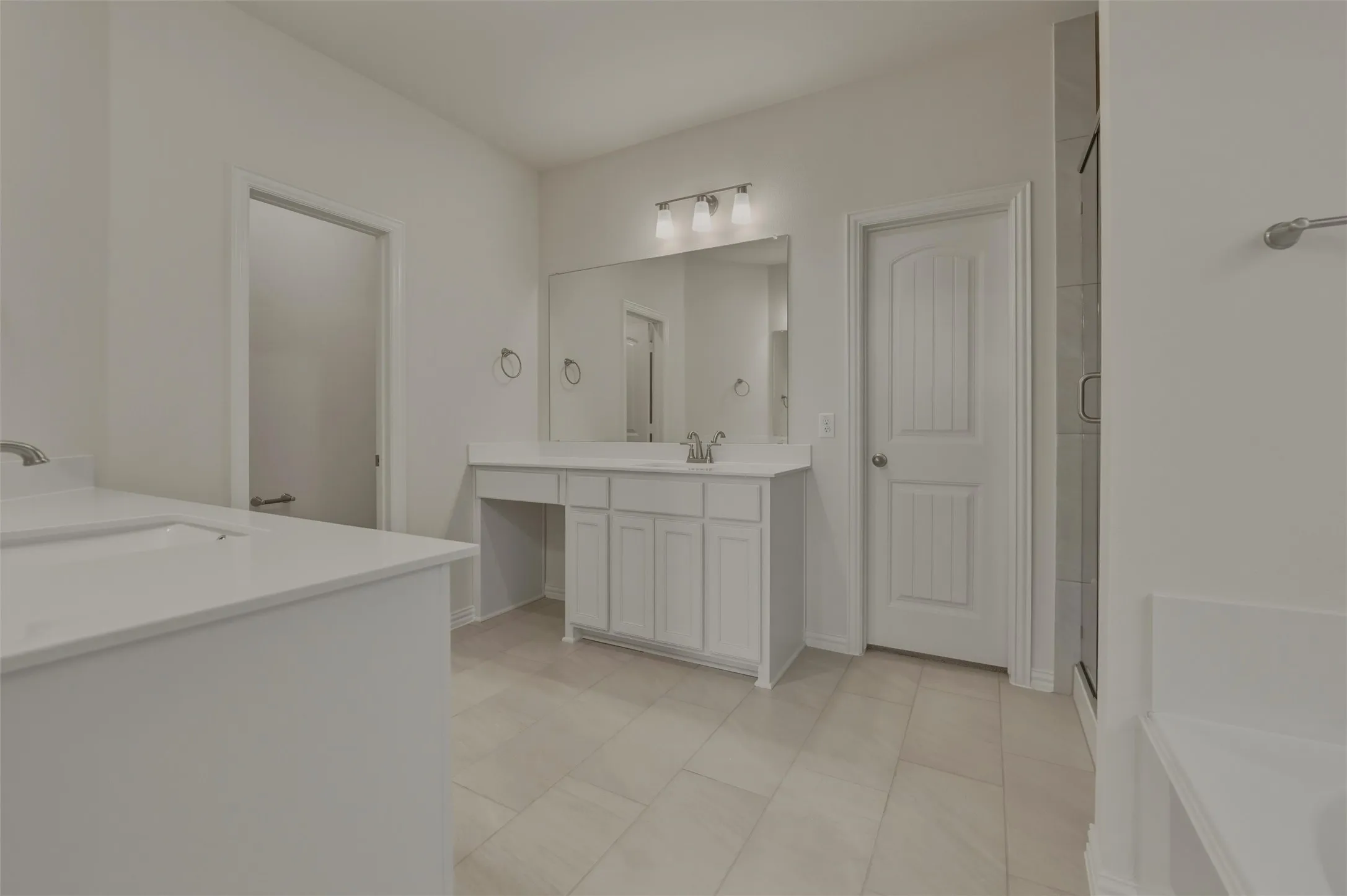 Dual vanity with integrated sinks, white cabinetry, vanity counter, tiled flooring, and a glass-enclosed shower