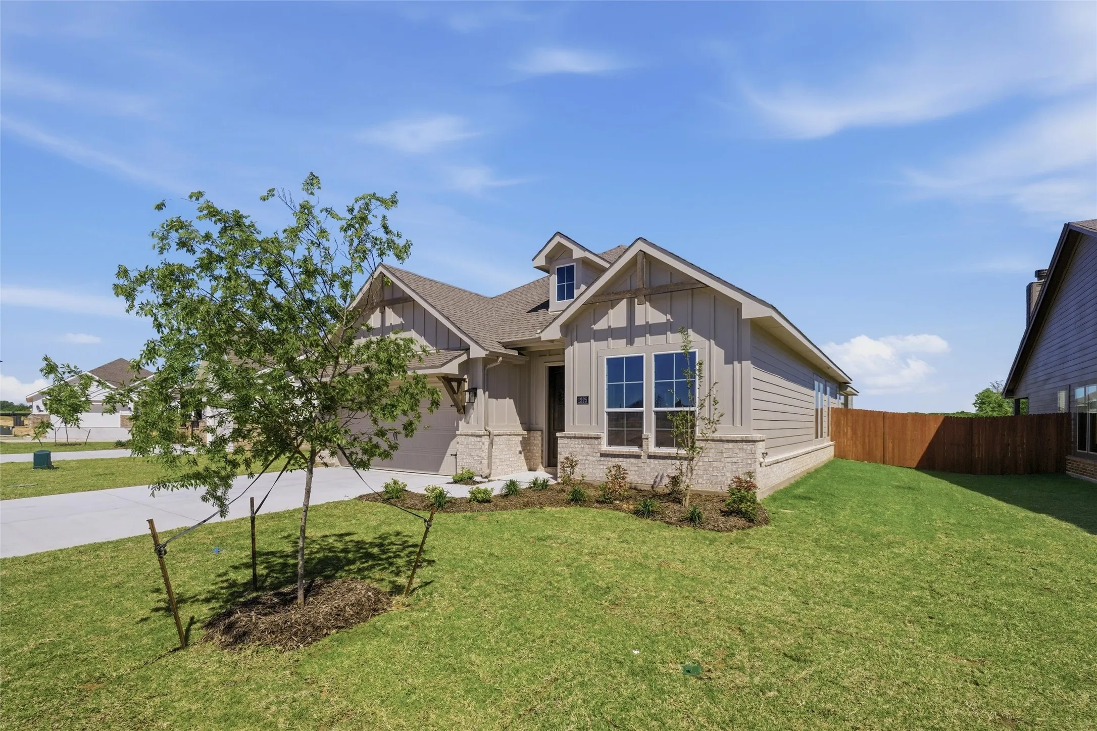Craftsman inspired home with board and batten siding, driveway, a garage, and brick siding