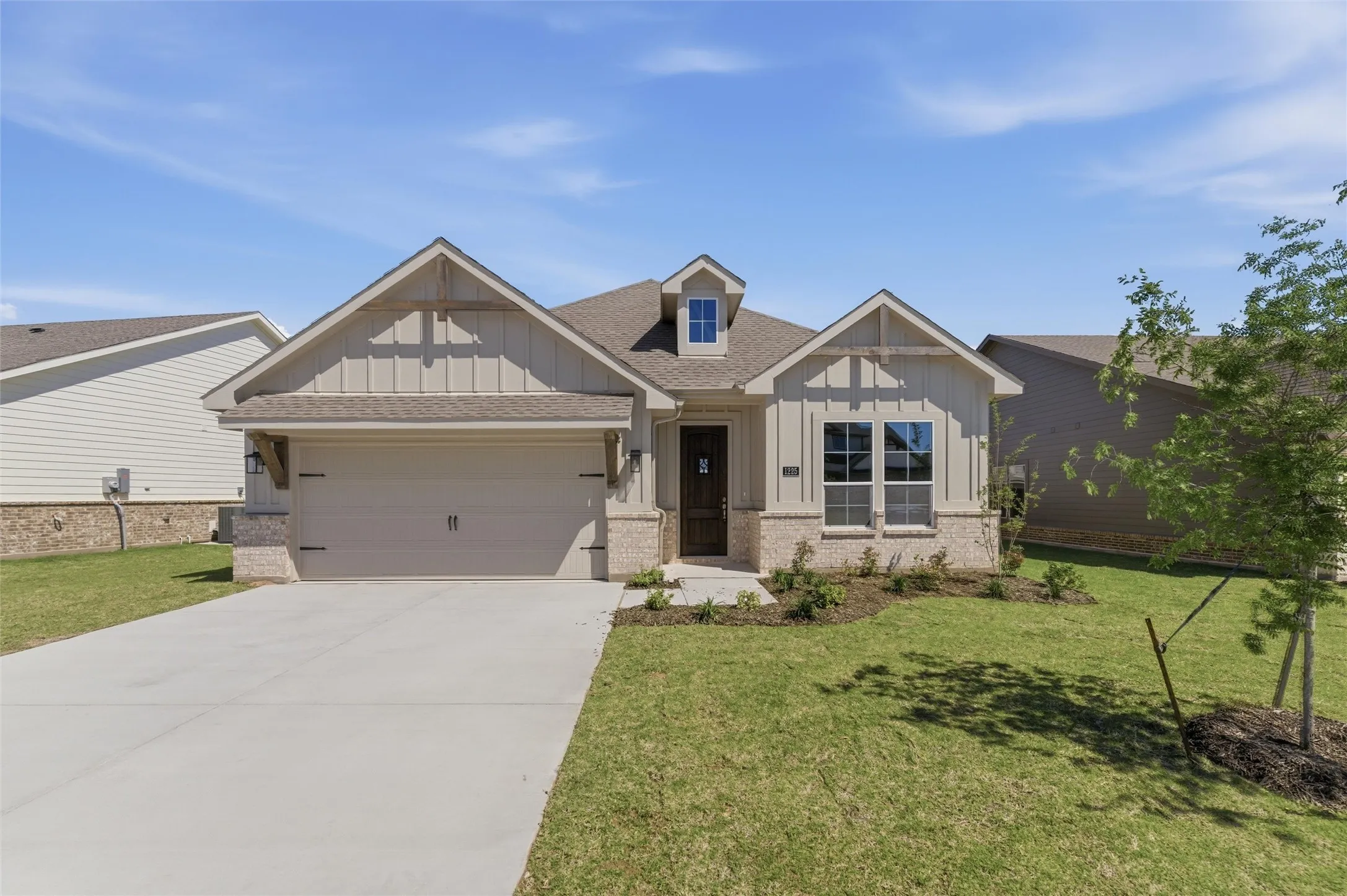 Craftsman-style house featuring board and batten siding, brick siding, and a front lawn