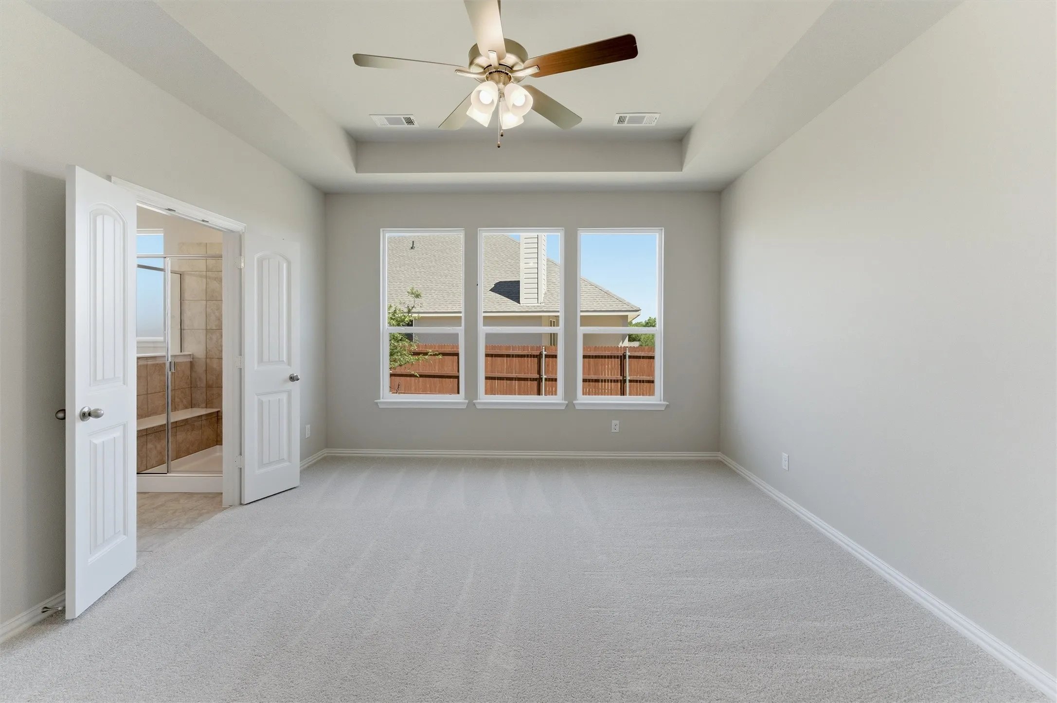 Spare room with ceiling fan, light carpet, and a tray ceiling