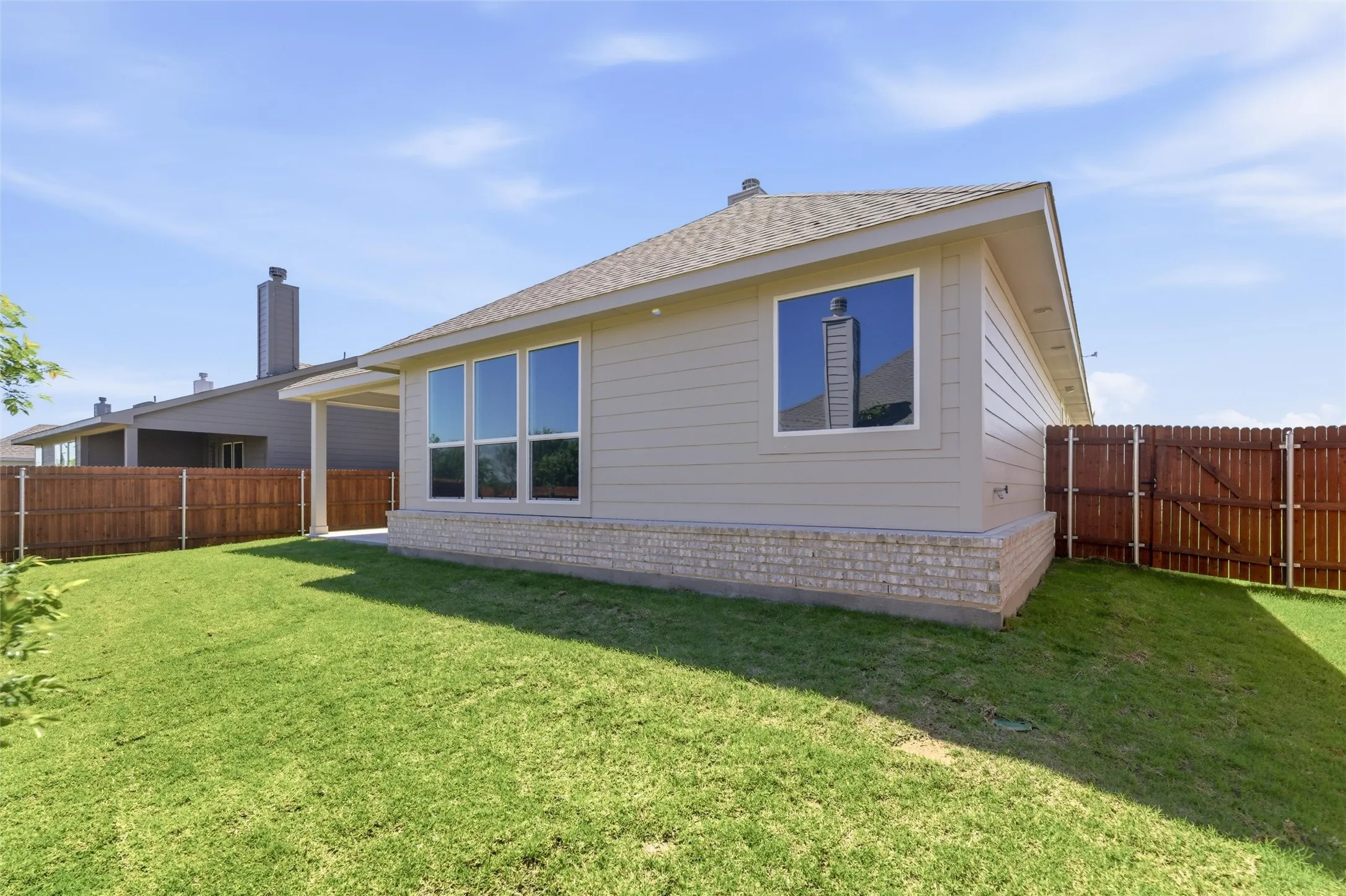 Rear view of property with a shingled roof, a fenced backyard, a gate, and a patio area