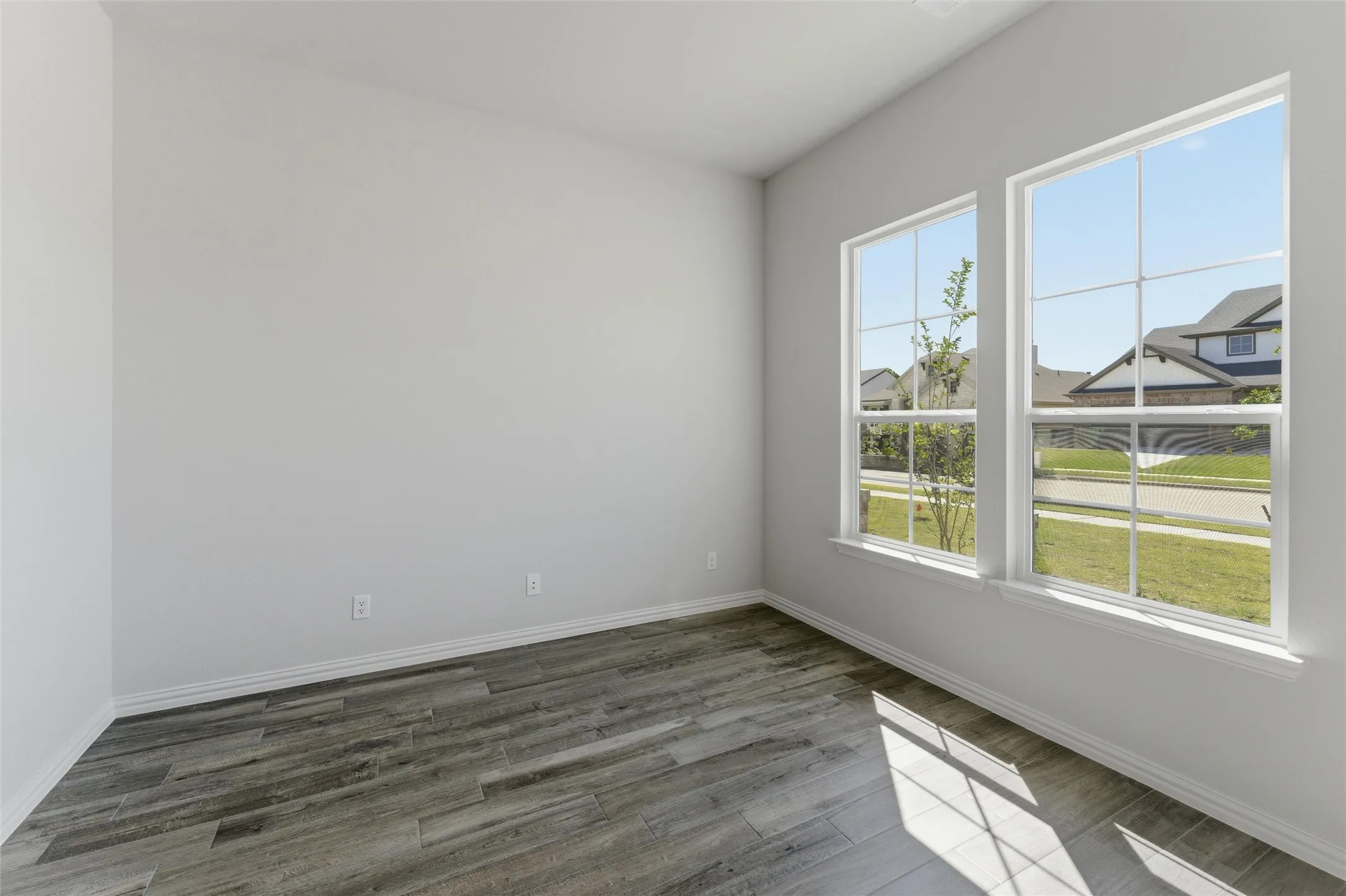 Empty room featuring dark wood finished floors and baseboards
