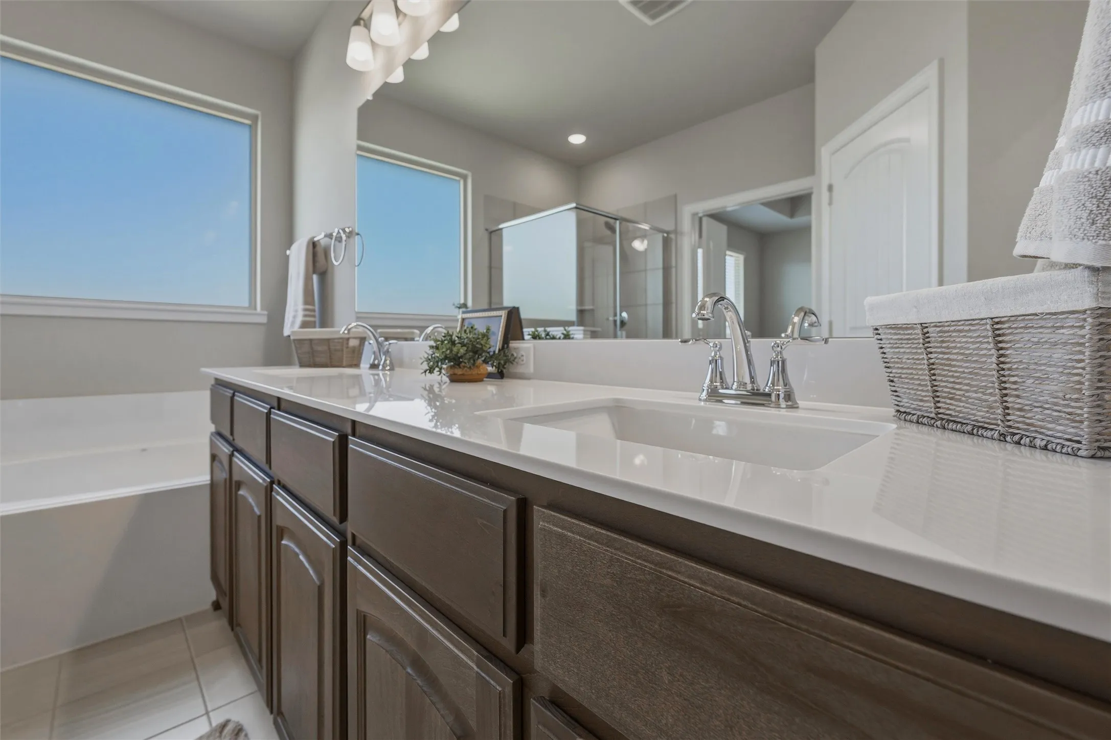 Dual vanity with integrated sinks and chrome fixtures, ample storage cabinetry, and a built-in tub