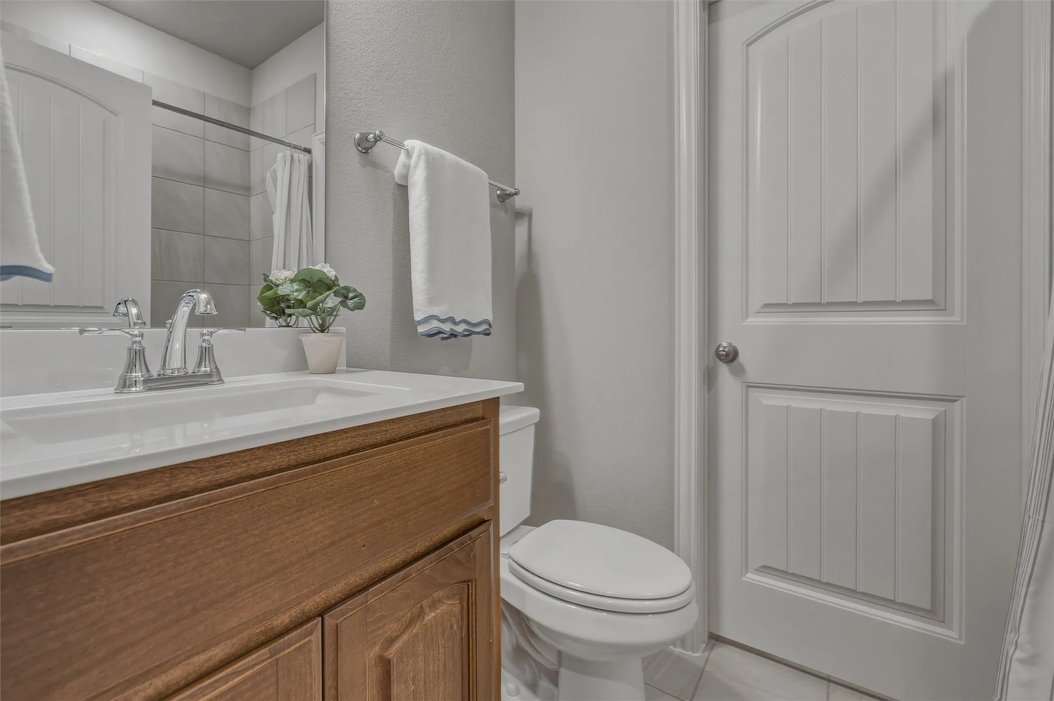Bathroom featuring a vanity with a white countertop and wood-finish cabinetry, a chrome faucet, and a toilet