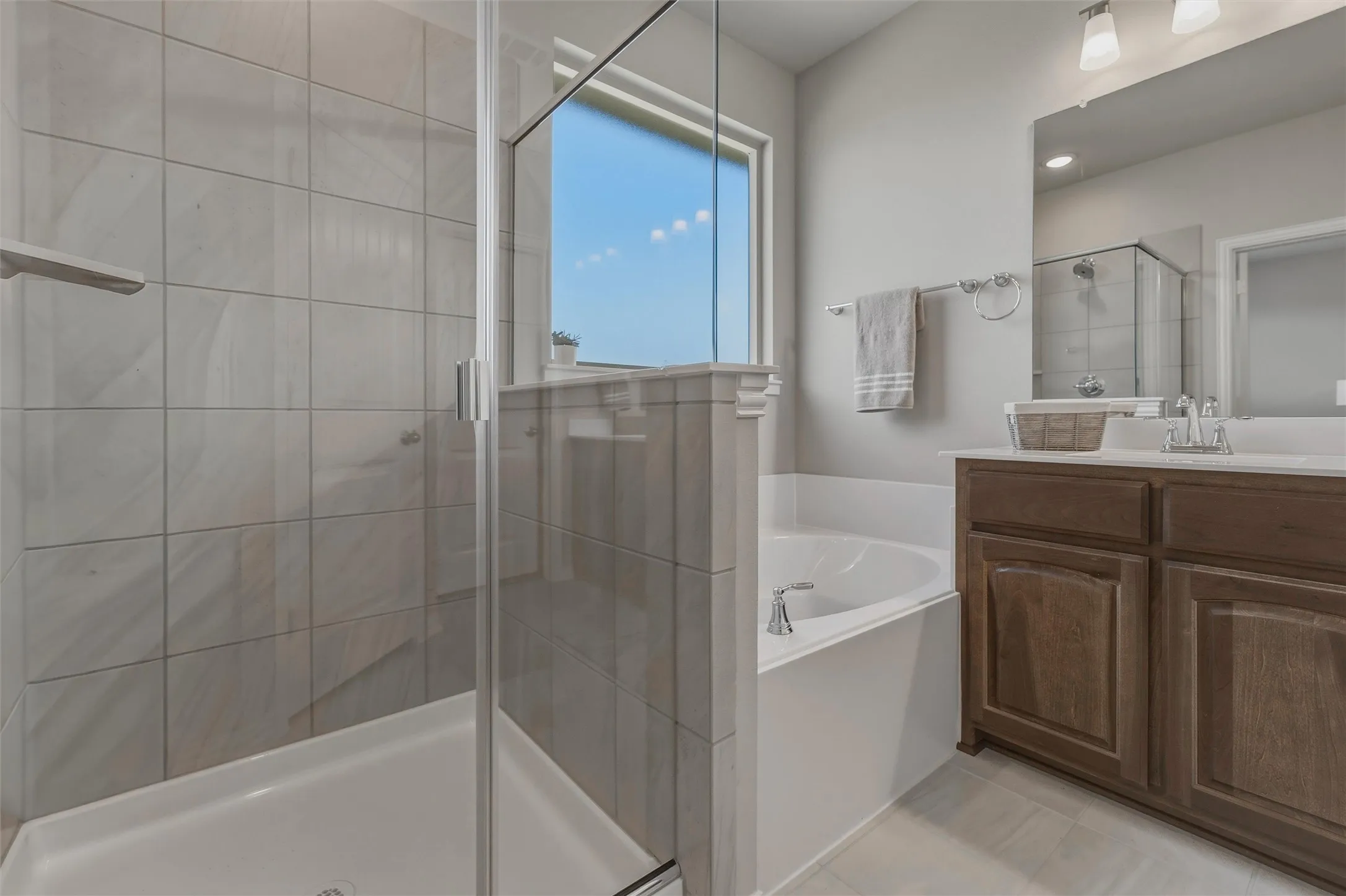 Glass-enclosed shower with subway tile surround, separate soaking tub, and a single vanity with wood-finish cabinetry