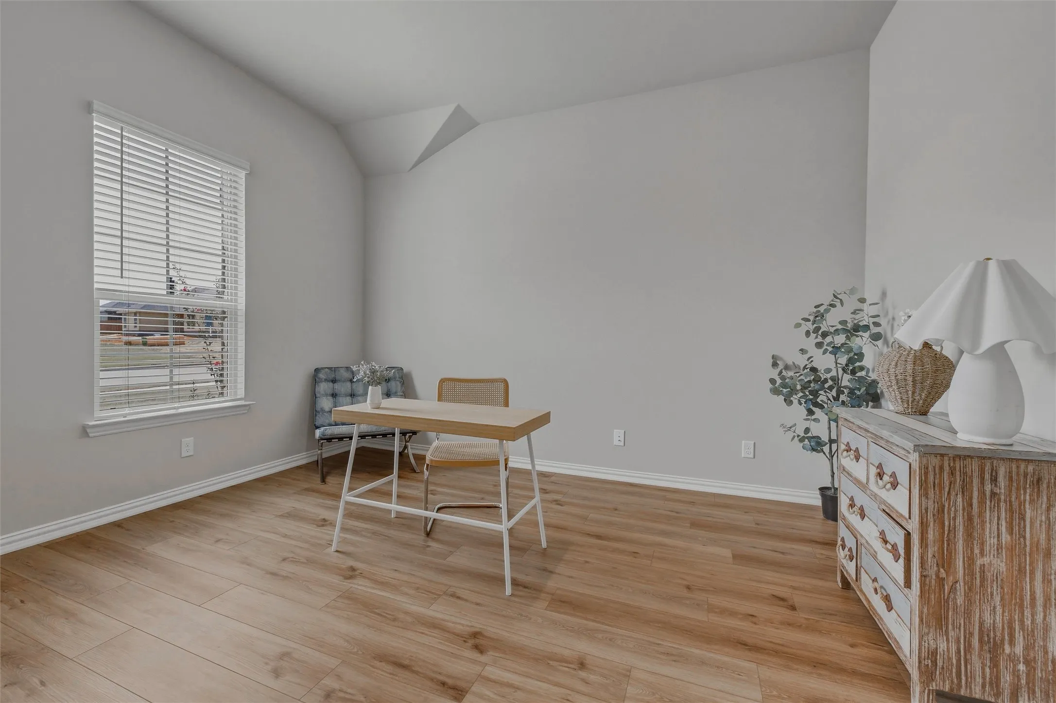 High vaulted ceilings, wood-finish flooring, and a large window with blinds