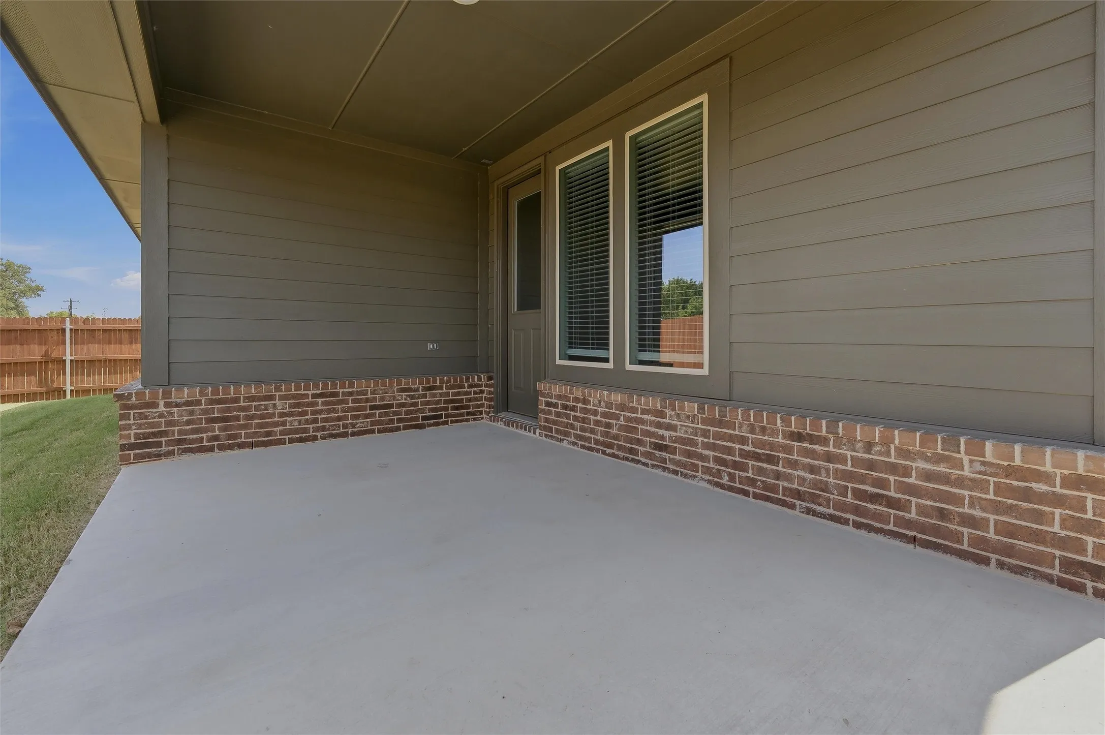Covered concrete patio featuring a brick and siding exterior