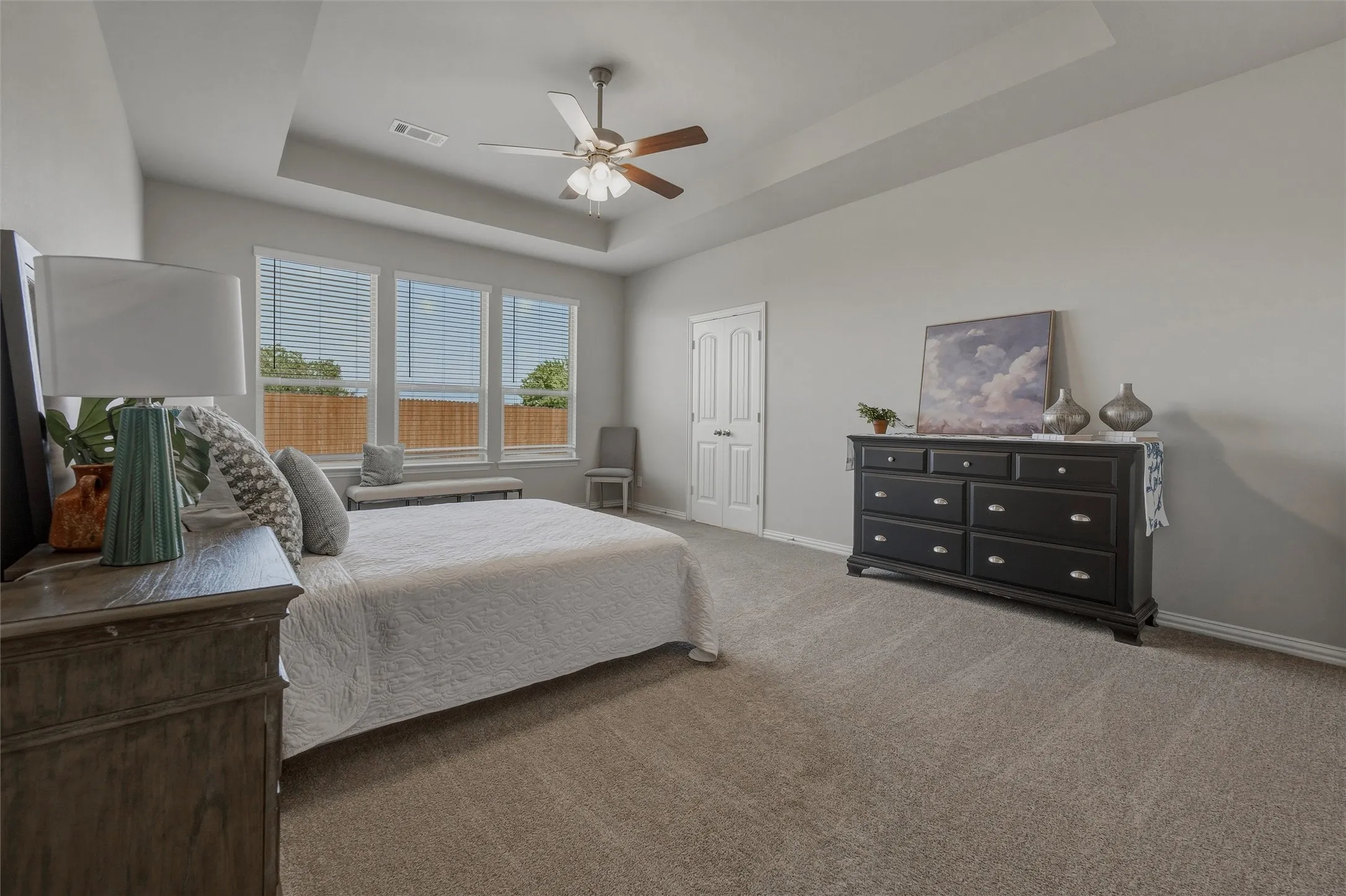 Tray ceiling with a ceiling fan, light gray wall paint, and carpet flooring