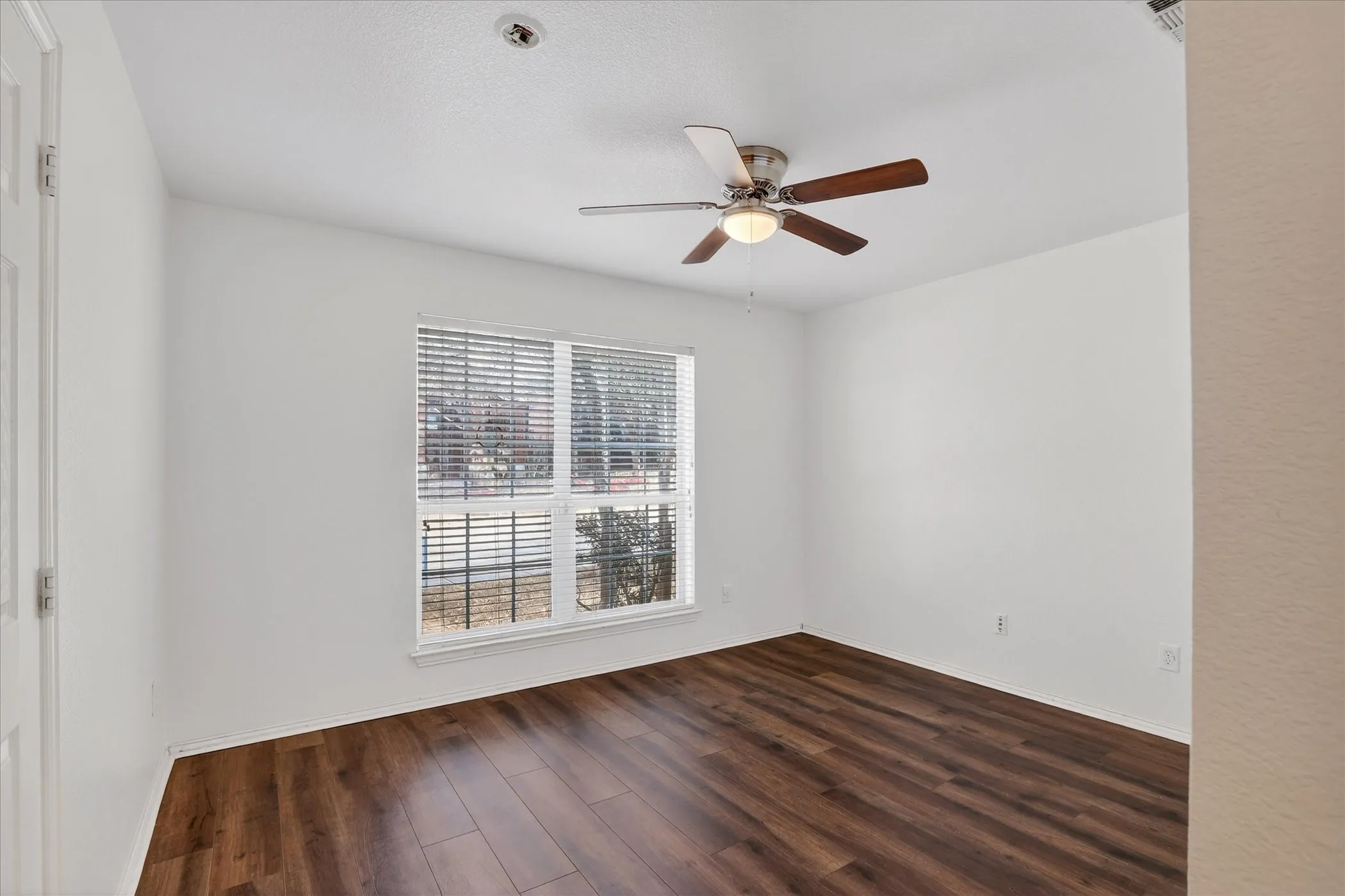 Empty room featuring ceiling fan and dark wood-style flooring