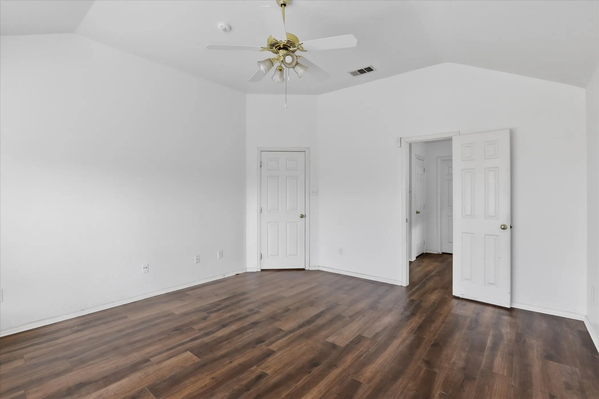Primary bedroom with dark wood finished floors and a ceiling fan