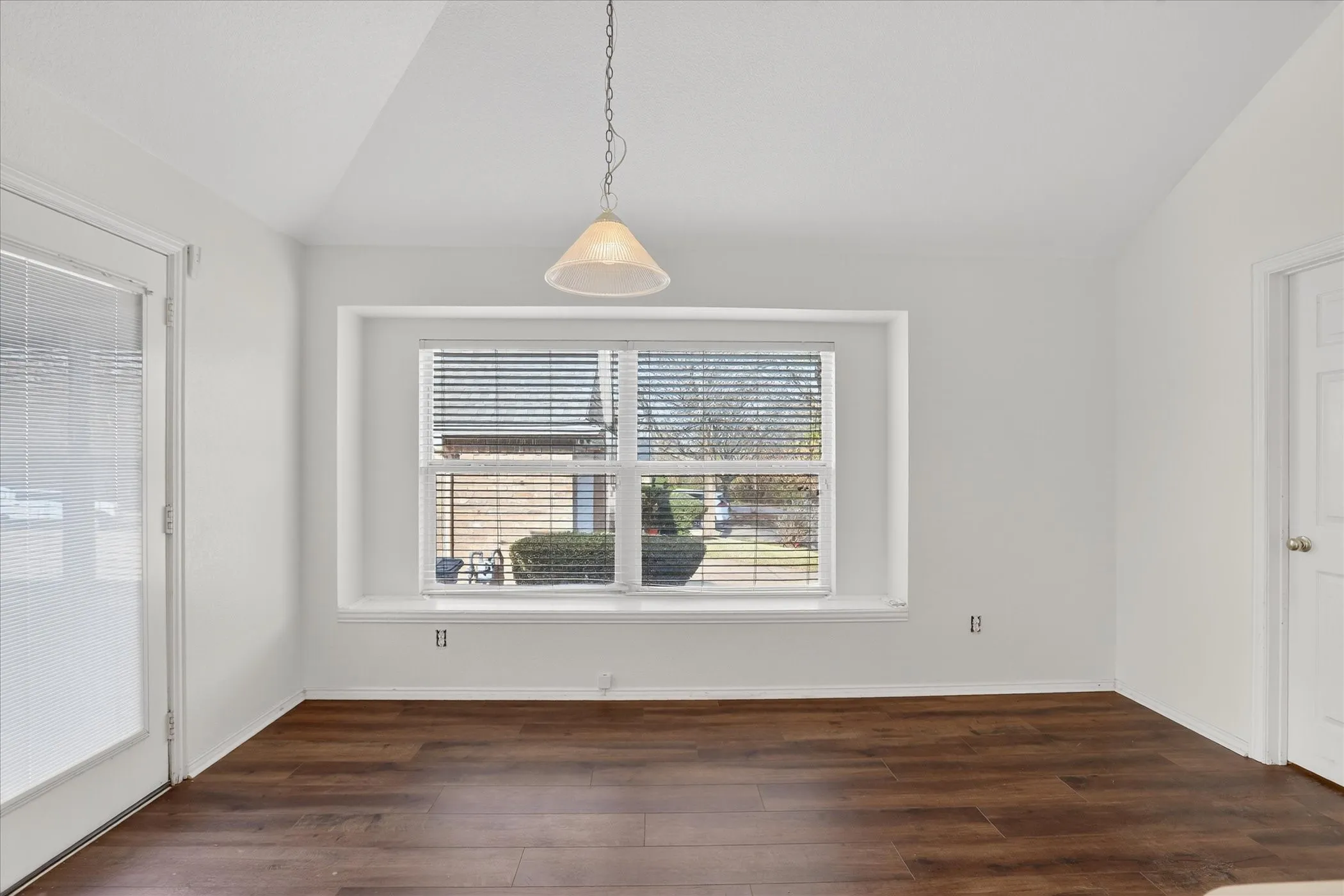 Unfurnished dining area featuring vaulted ceiling and dark wood-type flooring