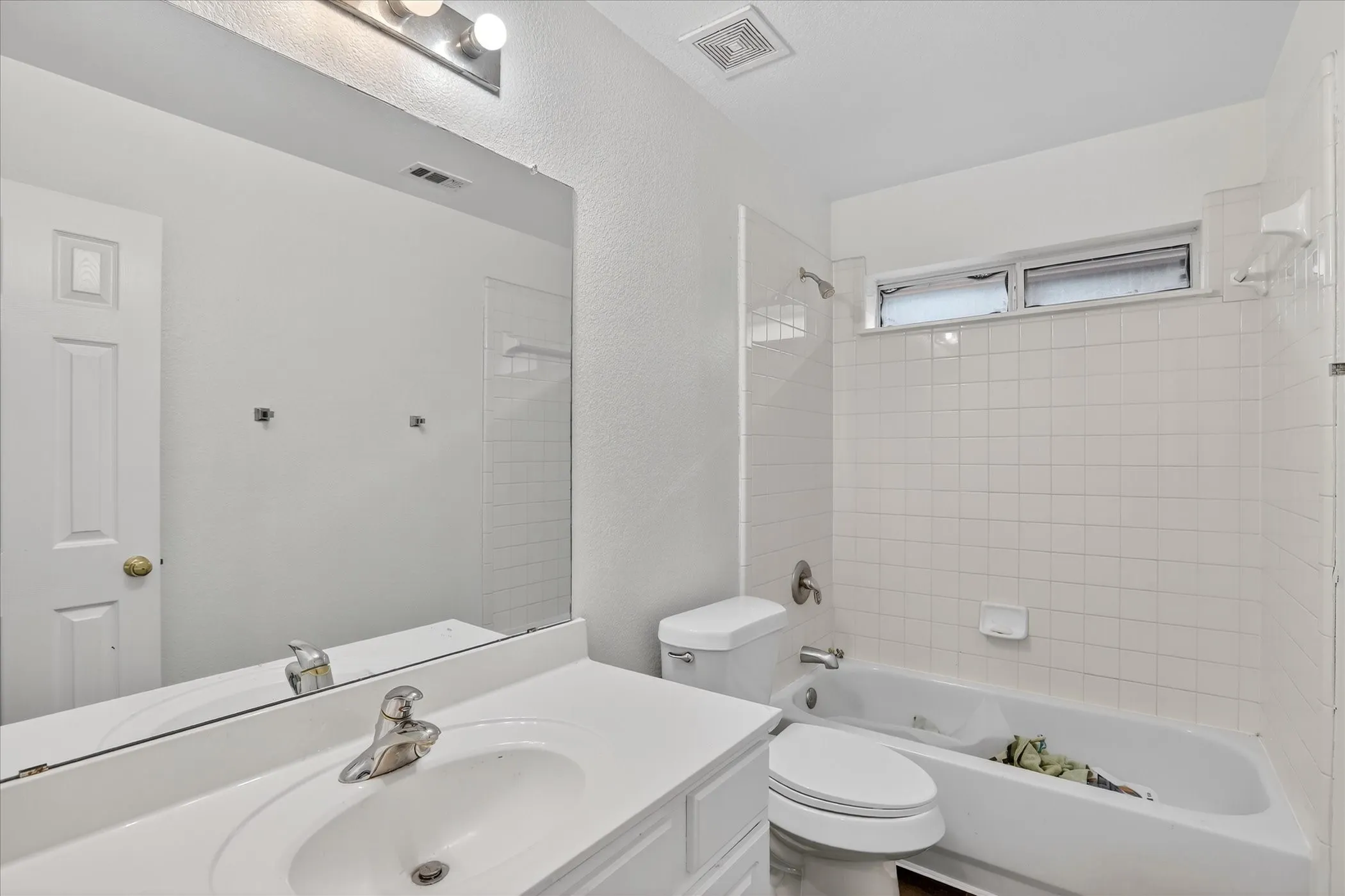 Bathroom featuring shower / bathtub combination, vanity, and a textured wall