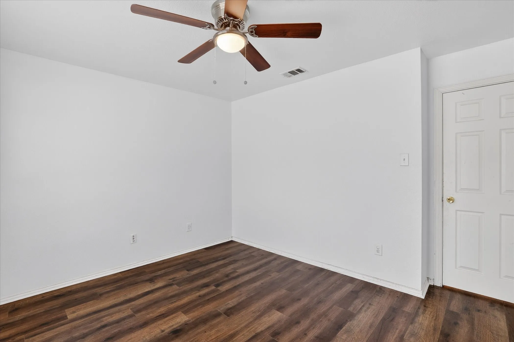 Unfurnished room featuring a ceiling fan and dark wood-style flooring