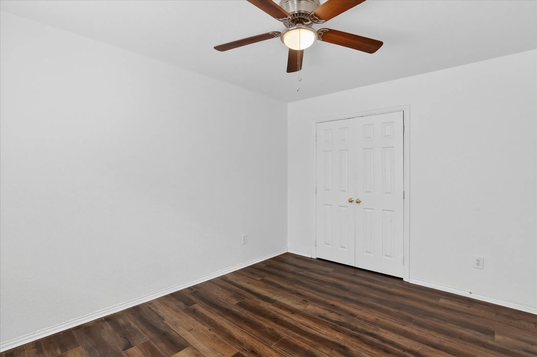 Unfurnished bedroom featuring dark wood finished floors, ceiling fan, and a closet