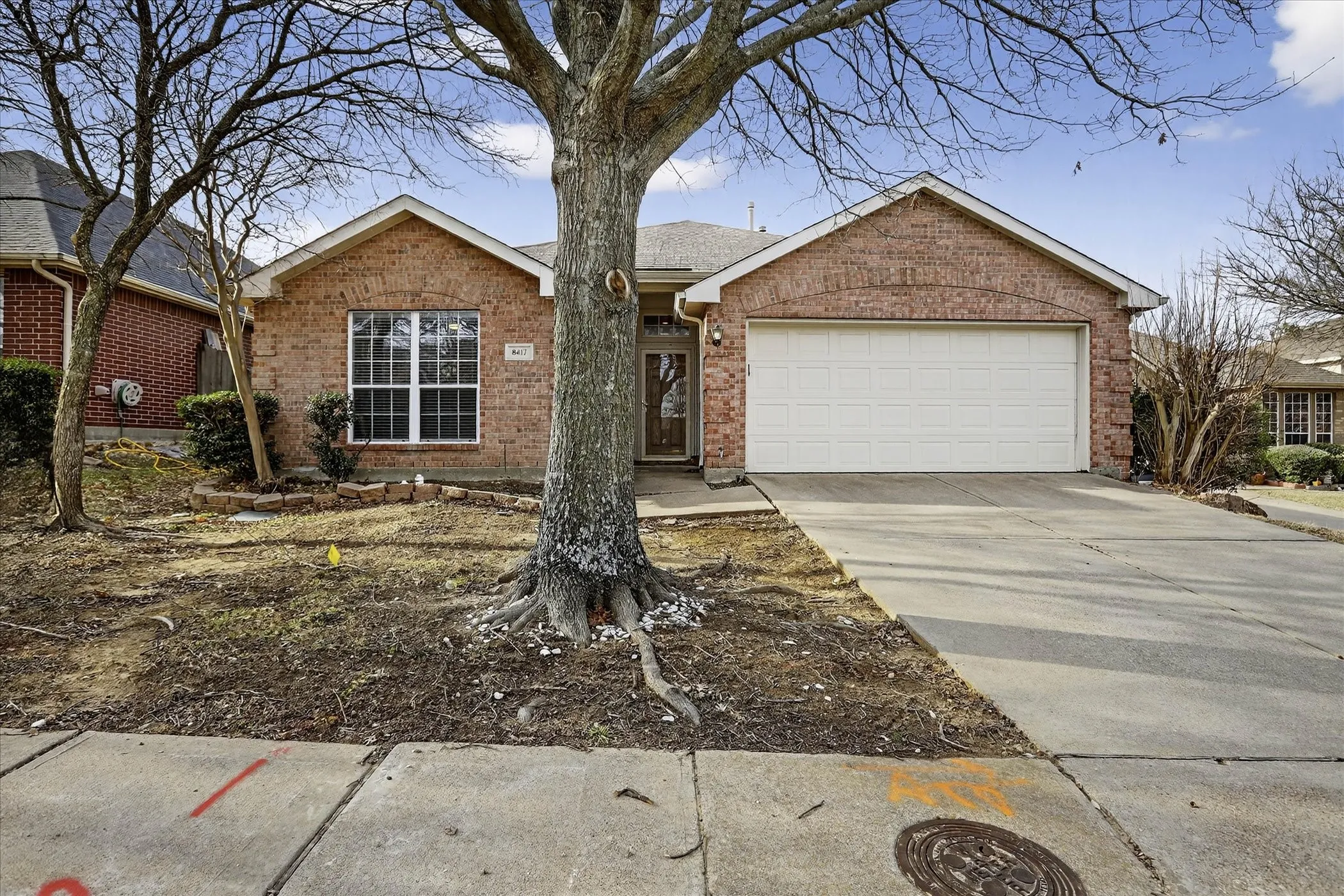 Ranch-style house featuring concrete driveway, an attached garage, and brick siding