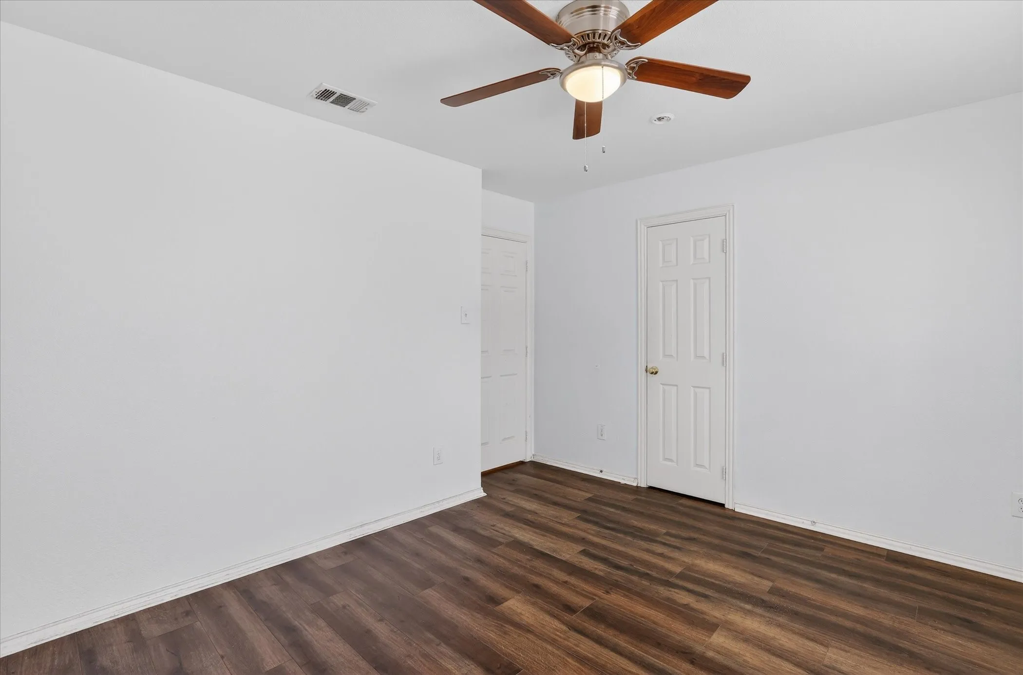 Unfurnished room featuring dark wood-style floors and a ceiling fan