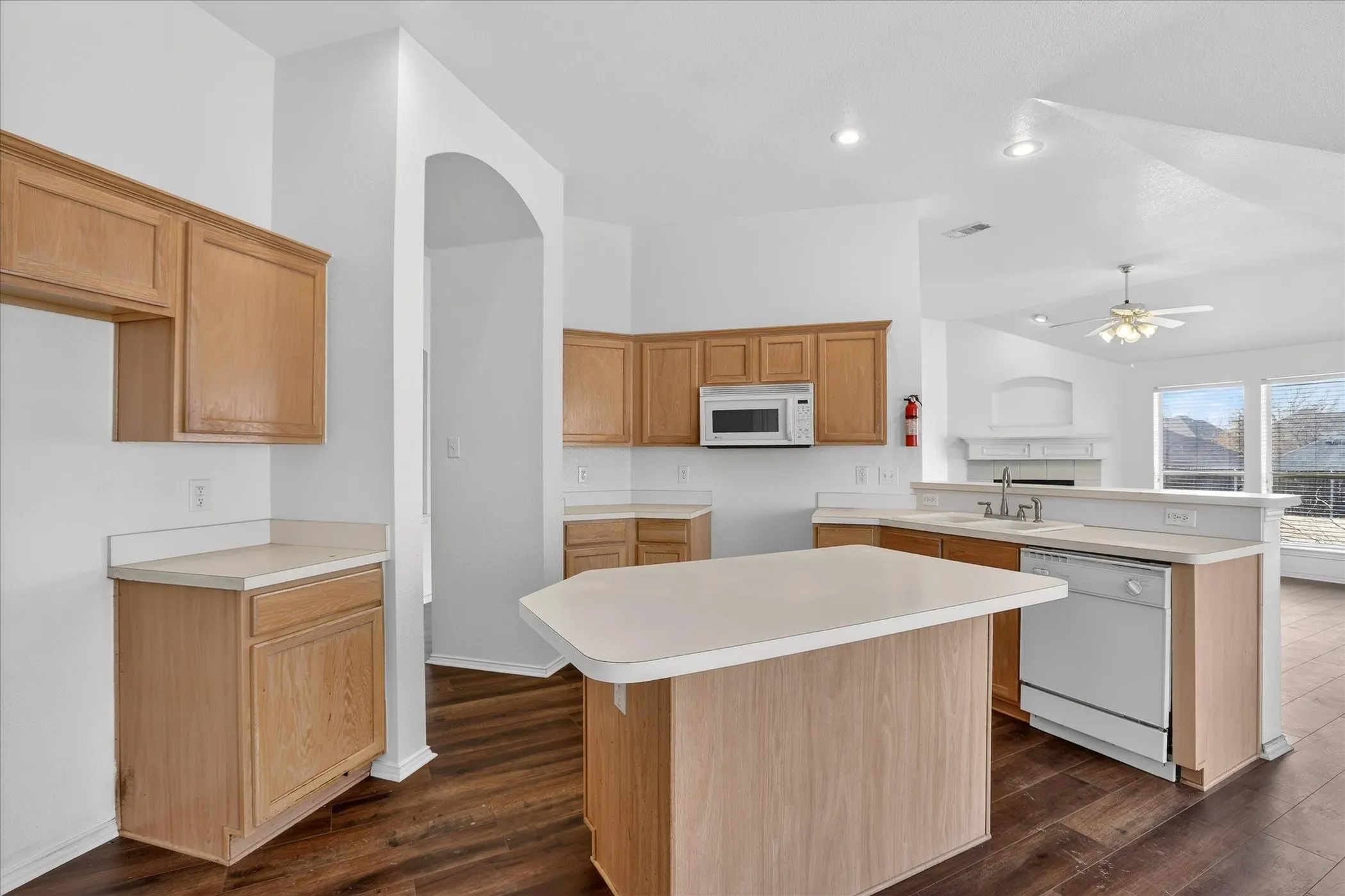 Kitchen featuring a peninsula, white appliances, light countertops, dark wood-style floors, and a ceiling fan