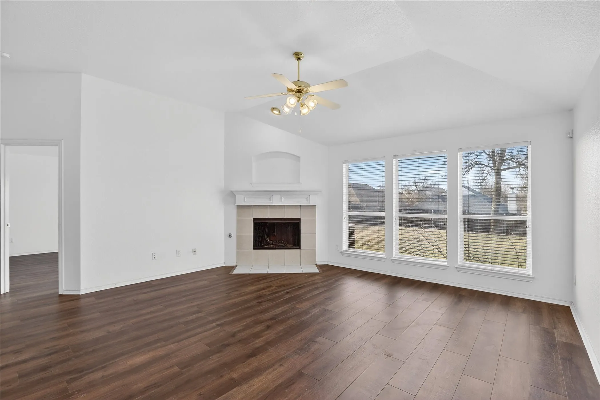 Unfurnished living room featuring a ceiling fan, a tile fireplace, dark wood-type flooring, and lofted ceiling