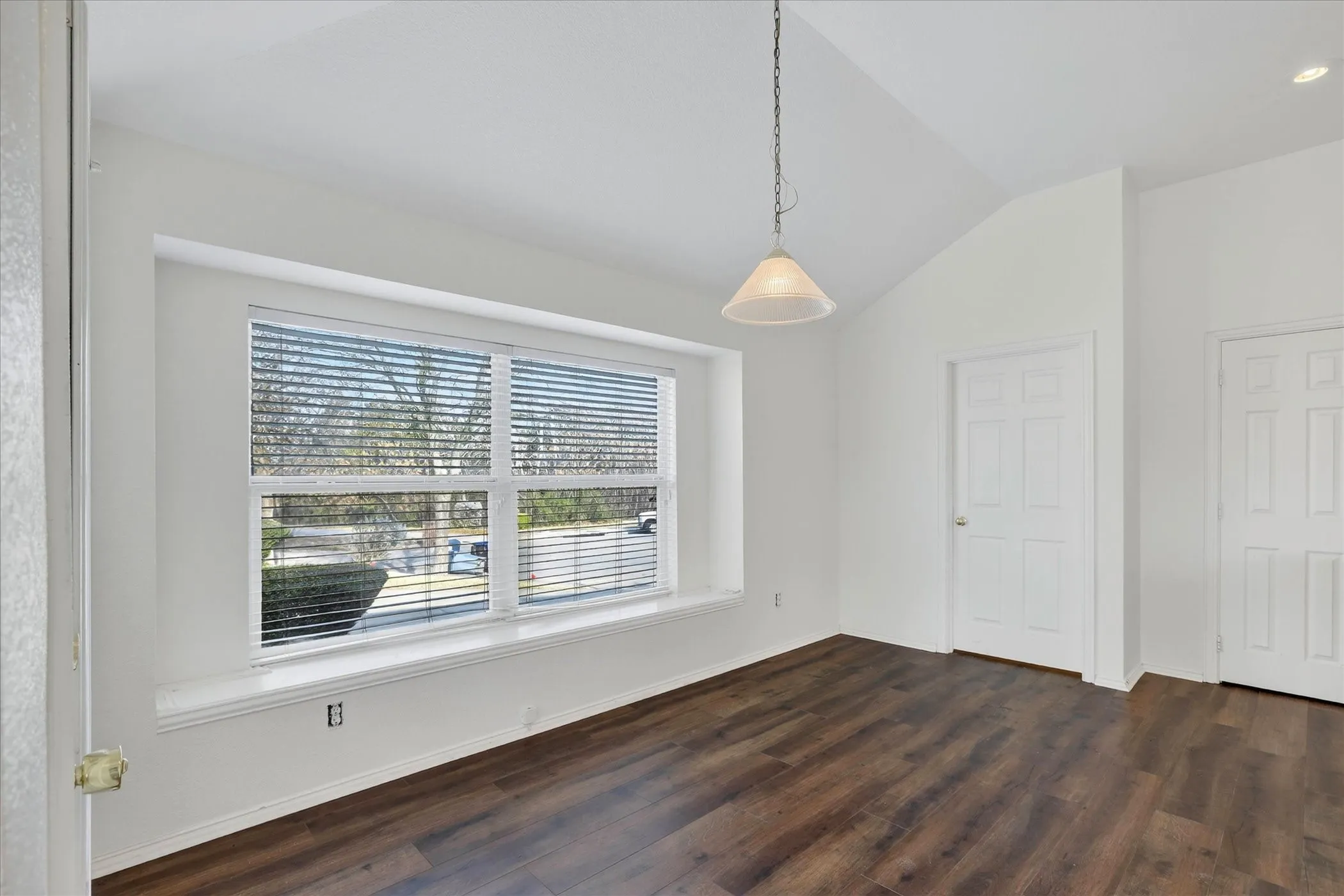 Unfurnished dining area featuring dark wood-style flooring and vaulted ceiling
