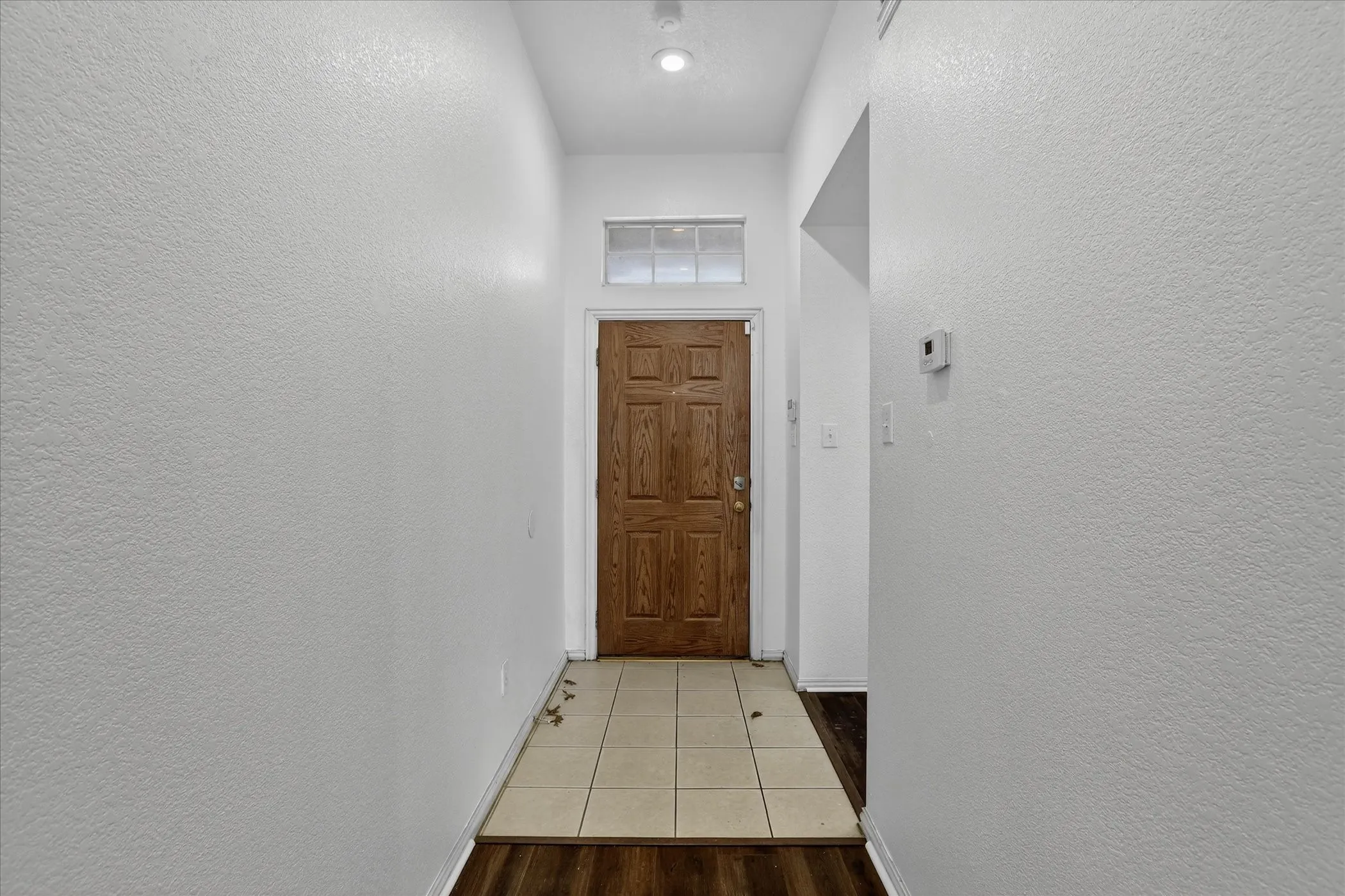 Doorway featuring a textured wall and tile patterned floors