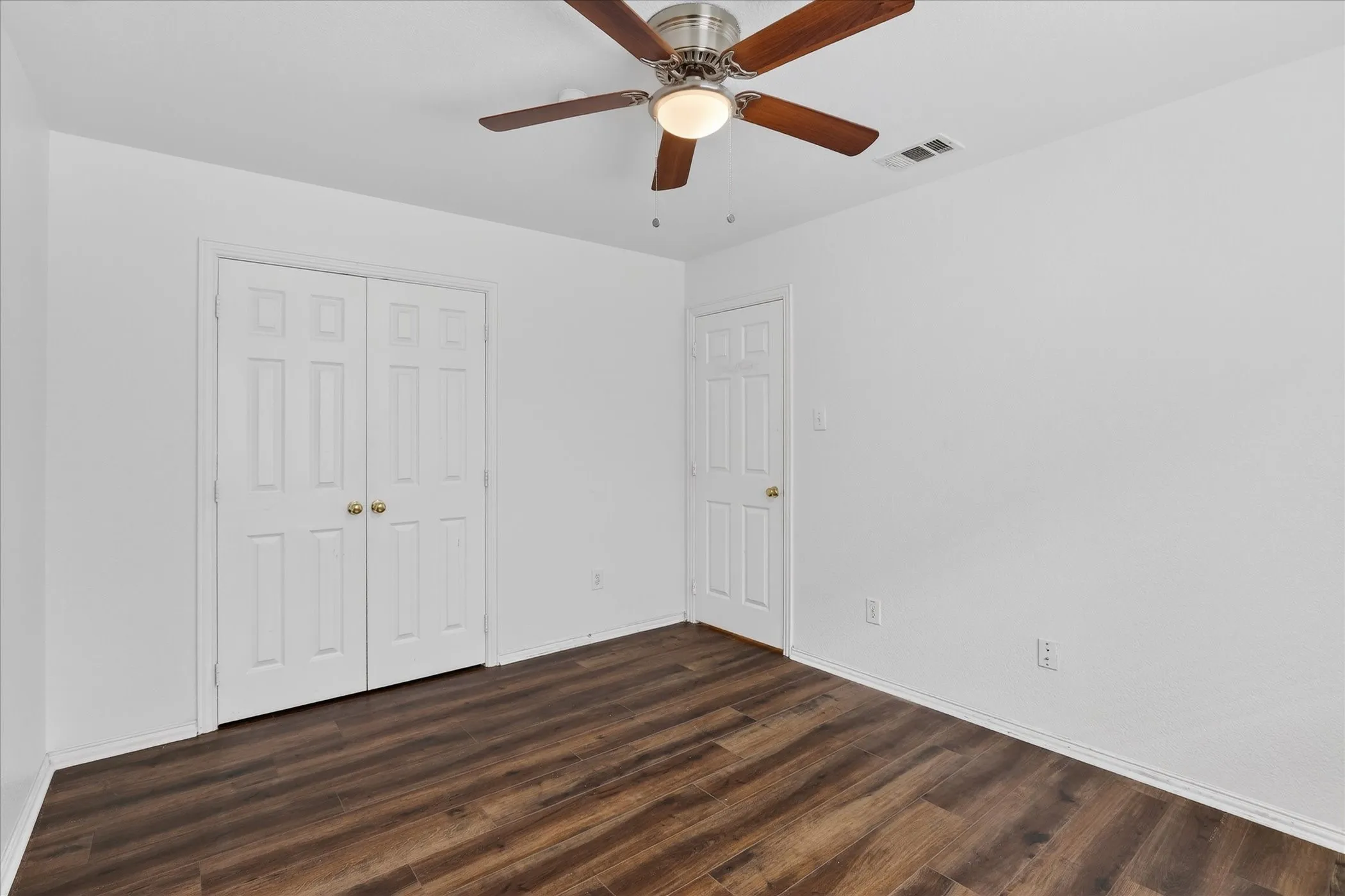 Unfurnished bedroom featuring a ceiling fan, a closet, and dark wood finished floors