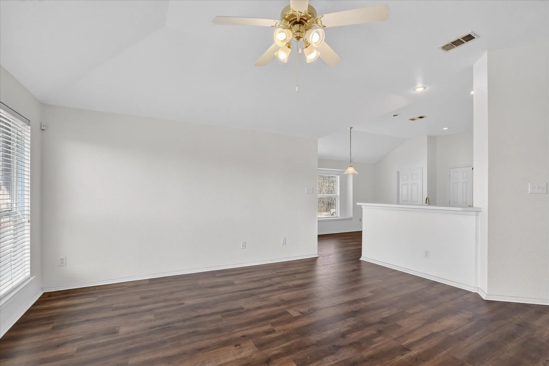 Empty room featuring vaulted ceiling, ceiling fan, dark wood-style floors, and recessed lighting