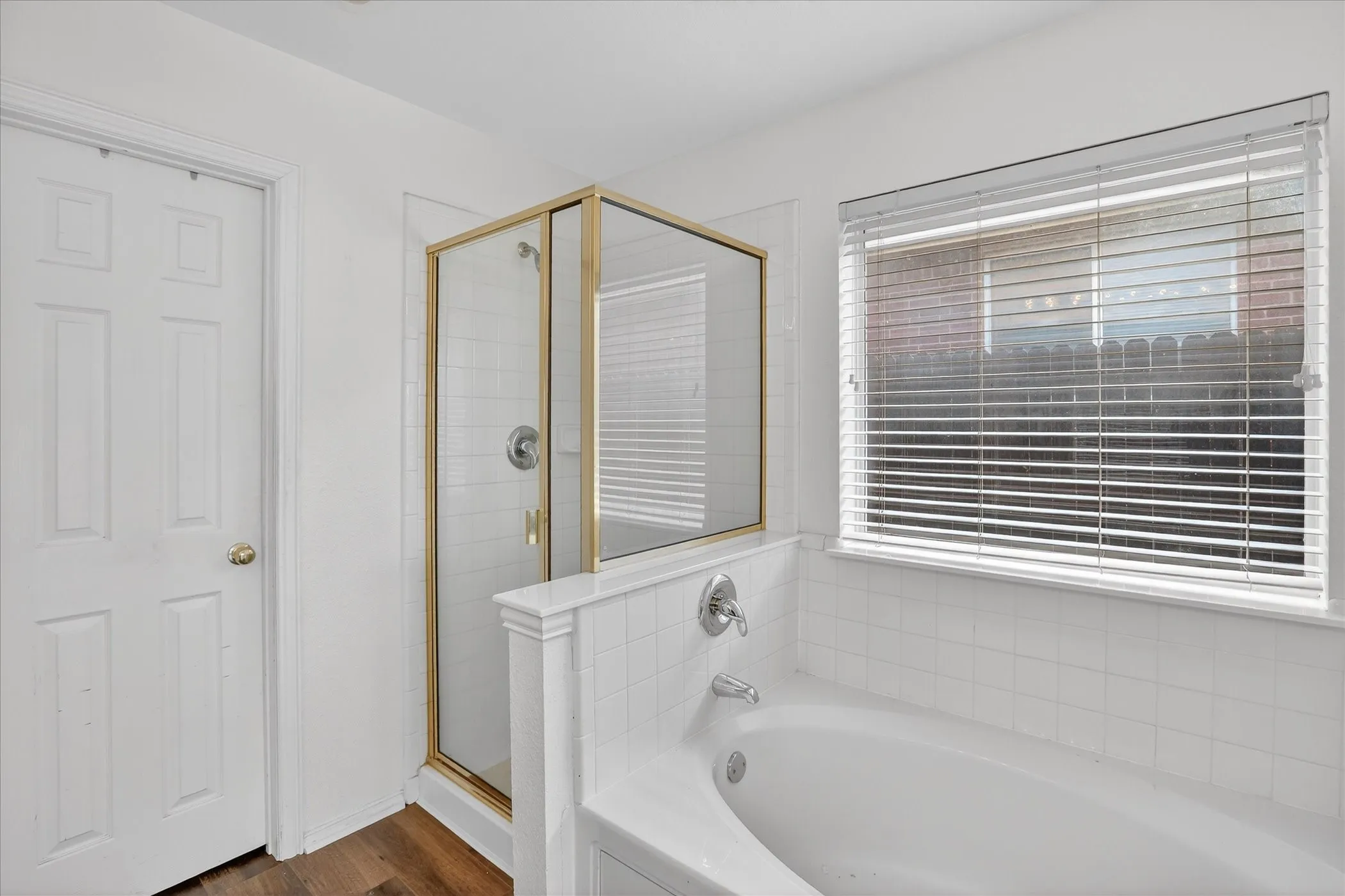 Bathroom with a shower stall, a garden tub, and dark wood-type flooring