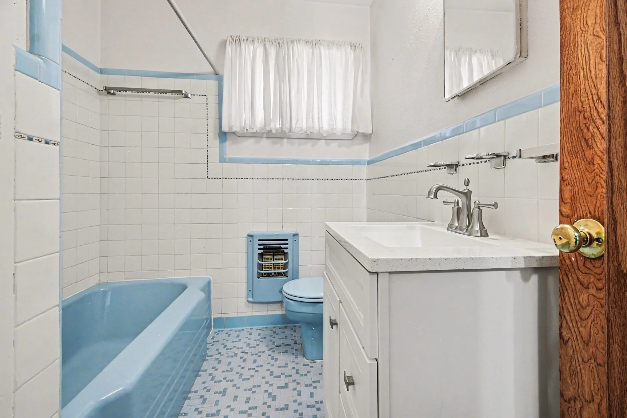 Full bath featuring a bathtub, vanity, tile walls, heating unit, and a wainscoted wall