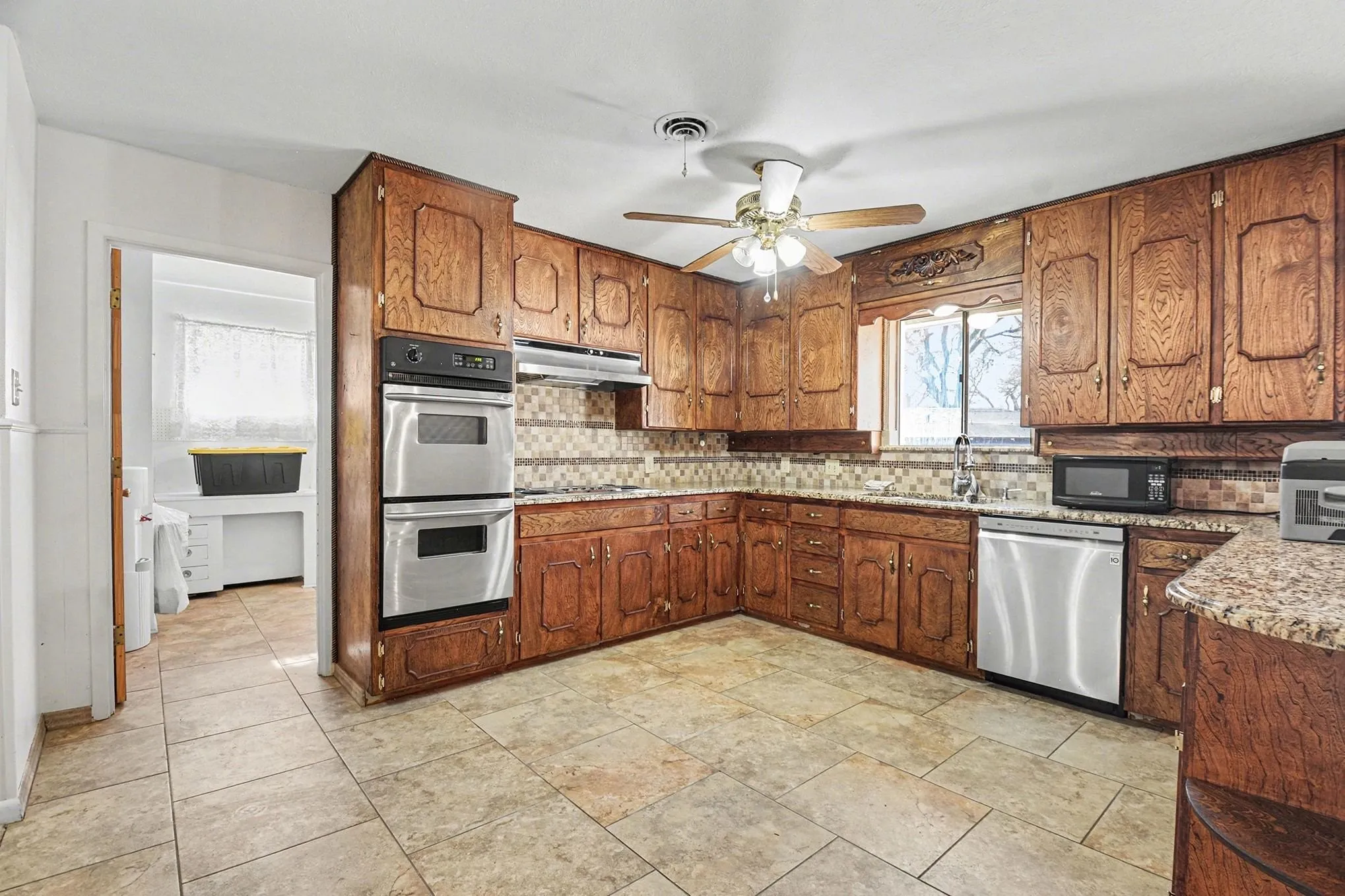 Kitchen with a peninsula, stainless steel appliances, light stone countertops, and ceiling fan