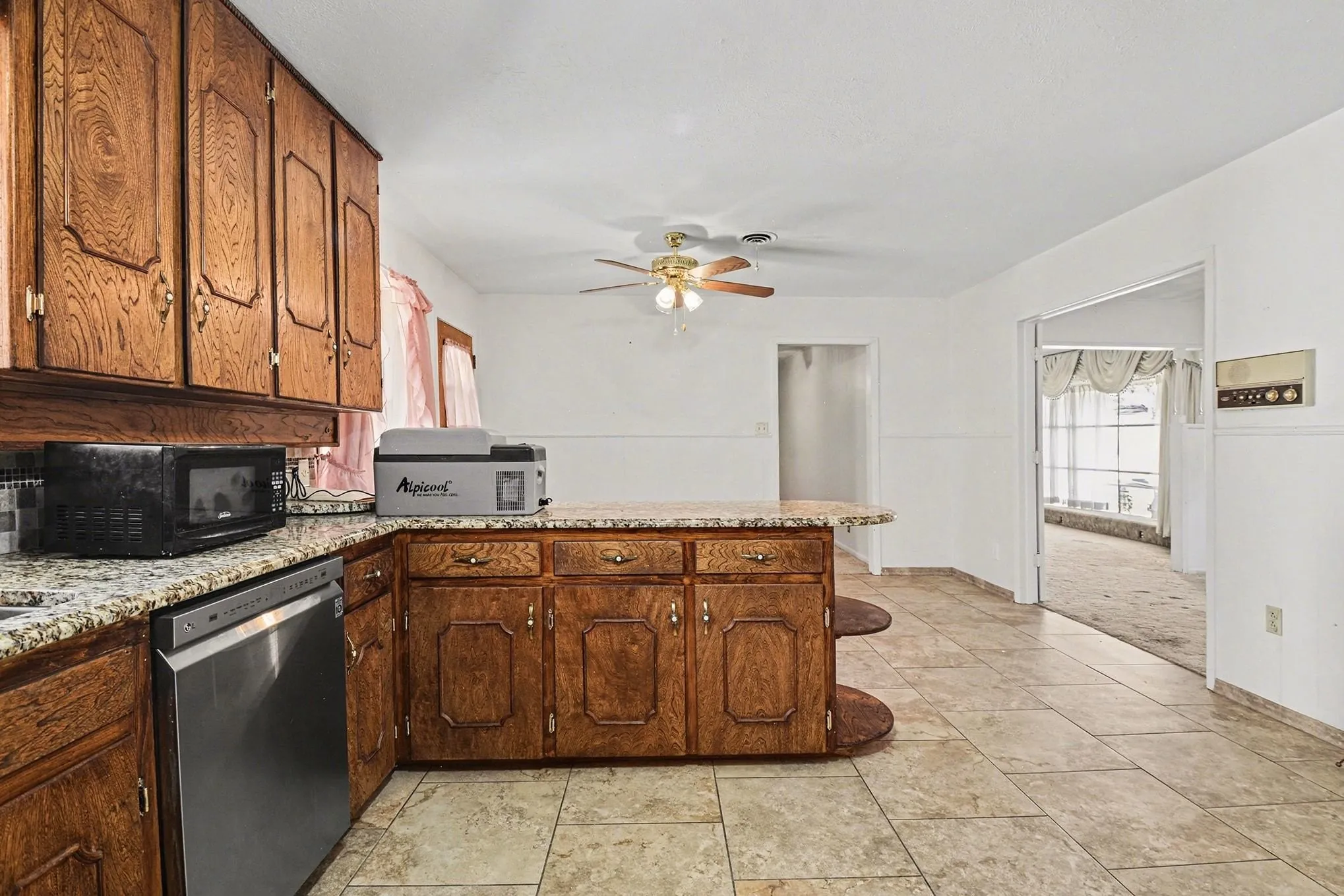Kitchen with a peninsula, stainless steel appliances, light stone countertops, and ceiling fan