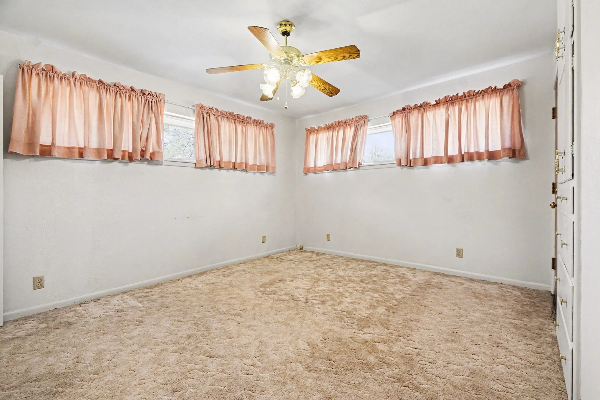 Spare room with ceiling fan, light colored carpet, and healthy amount of natural light