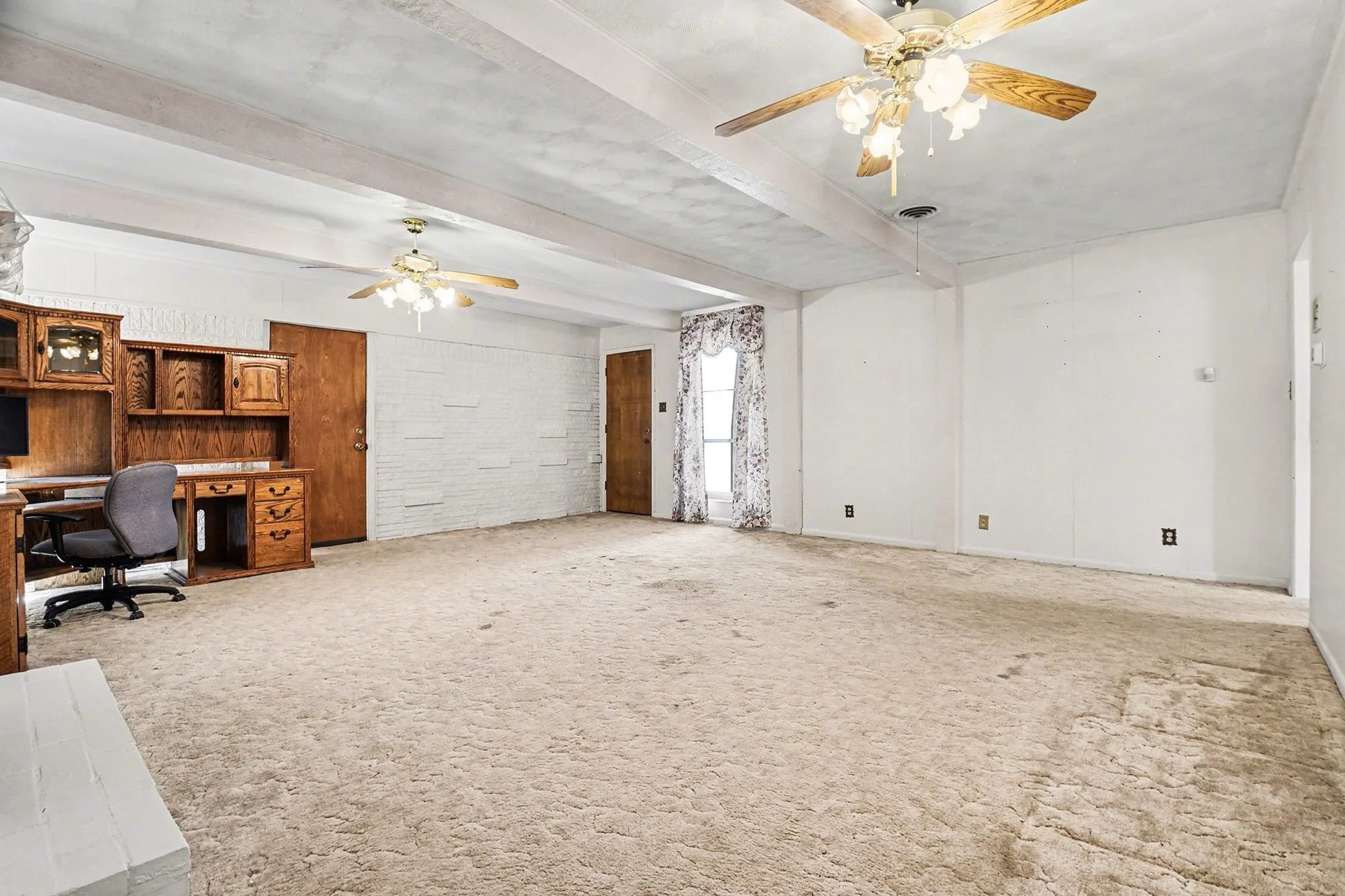 Unfurnished office featuring ceiling fan, beamed ceiling, and light colored carpet
