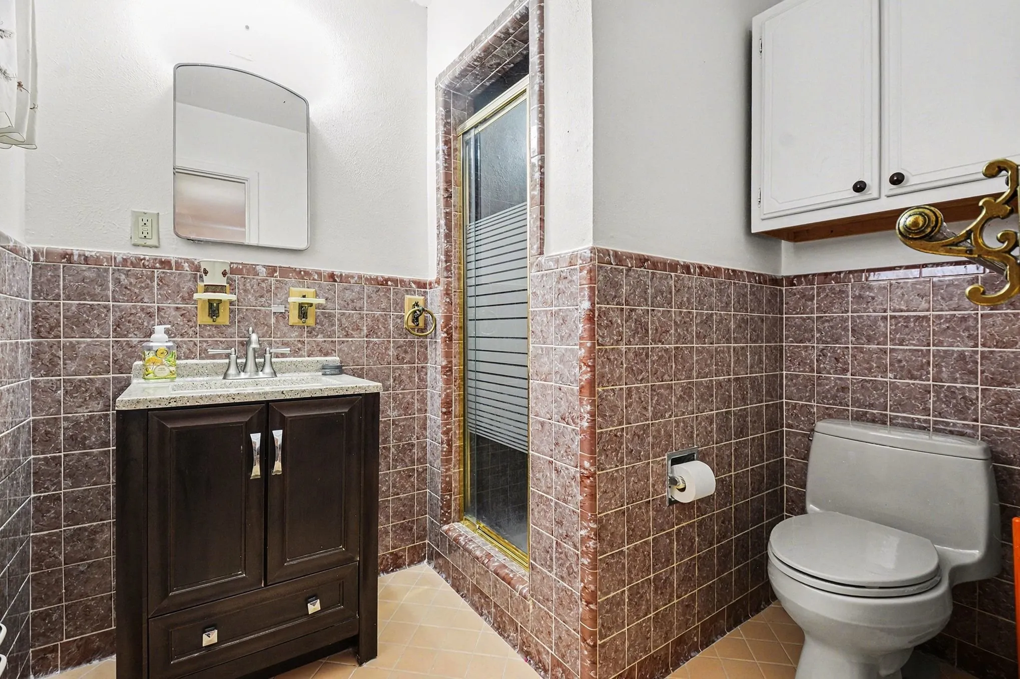 Full bath with tile walls, vanity, a stall shower, a wainscoted wall, and light tile patterned flooring