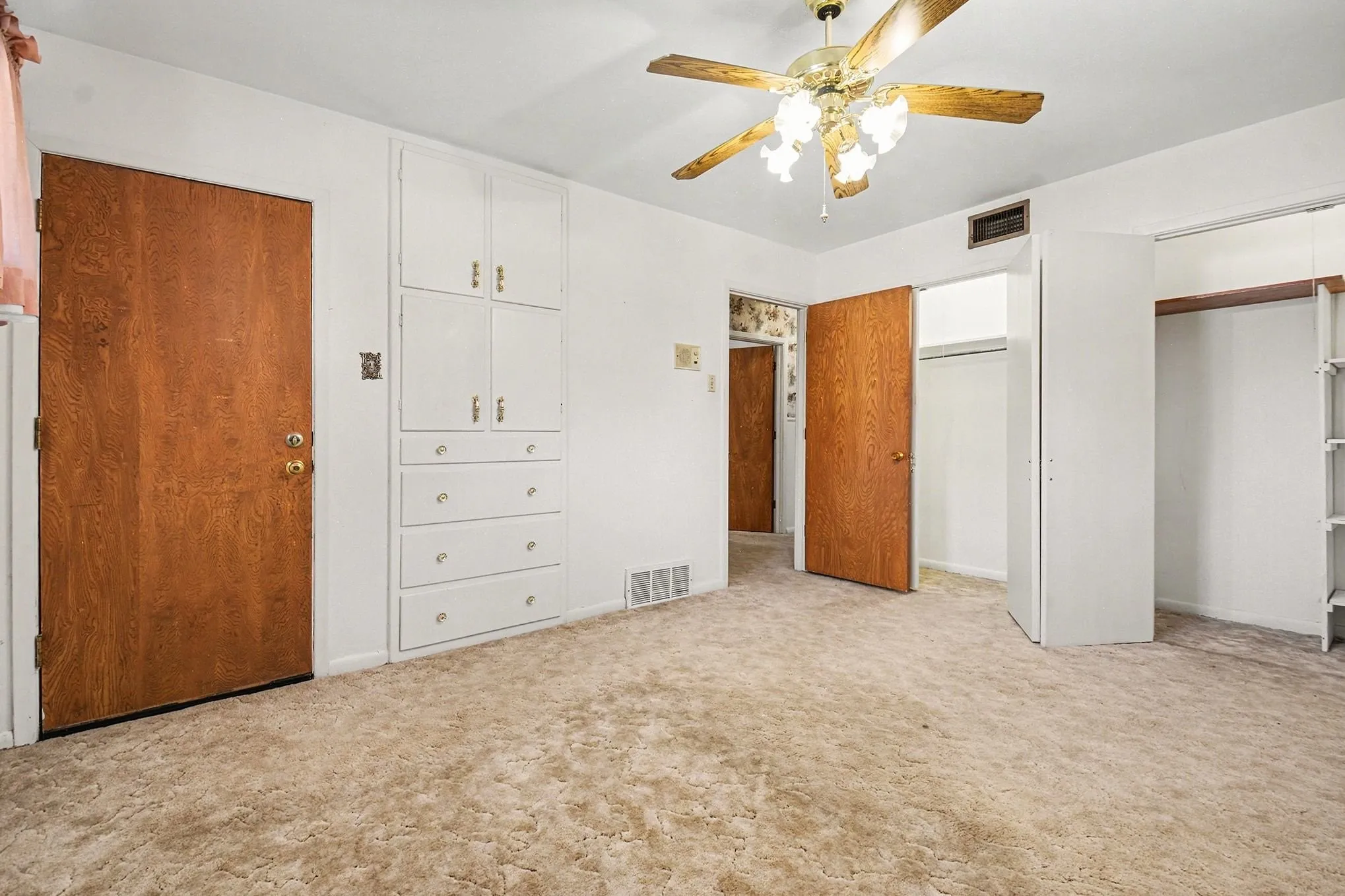 Unfurnished bedroom featuring two closets, a ceiling fan, and light colored carpet