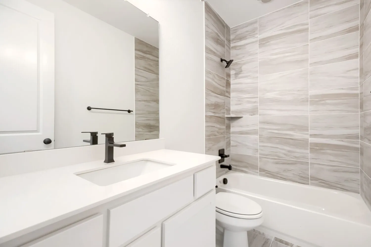 Bathroom featuring a white vanity with an integrated sink, dark bronze fixtures, and a large wall mirror
