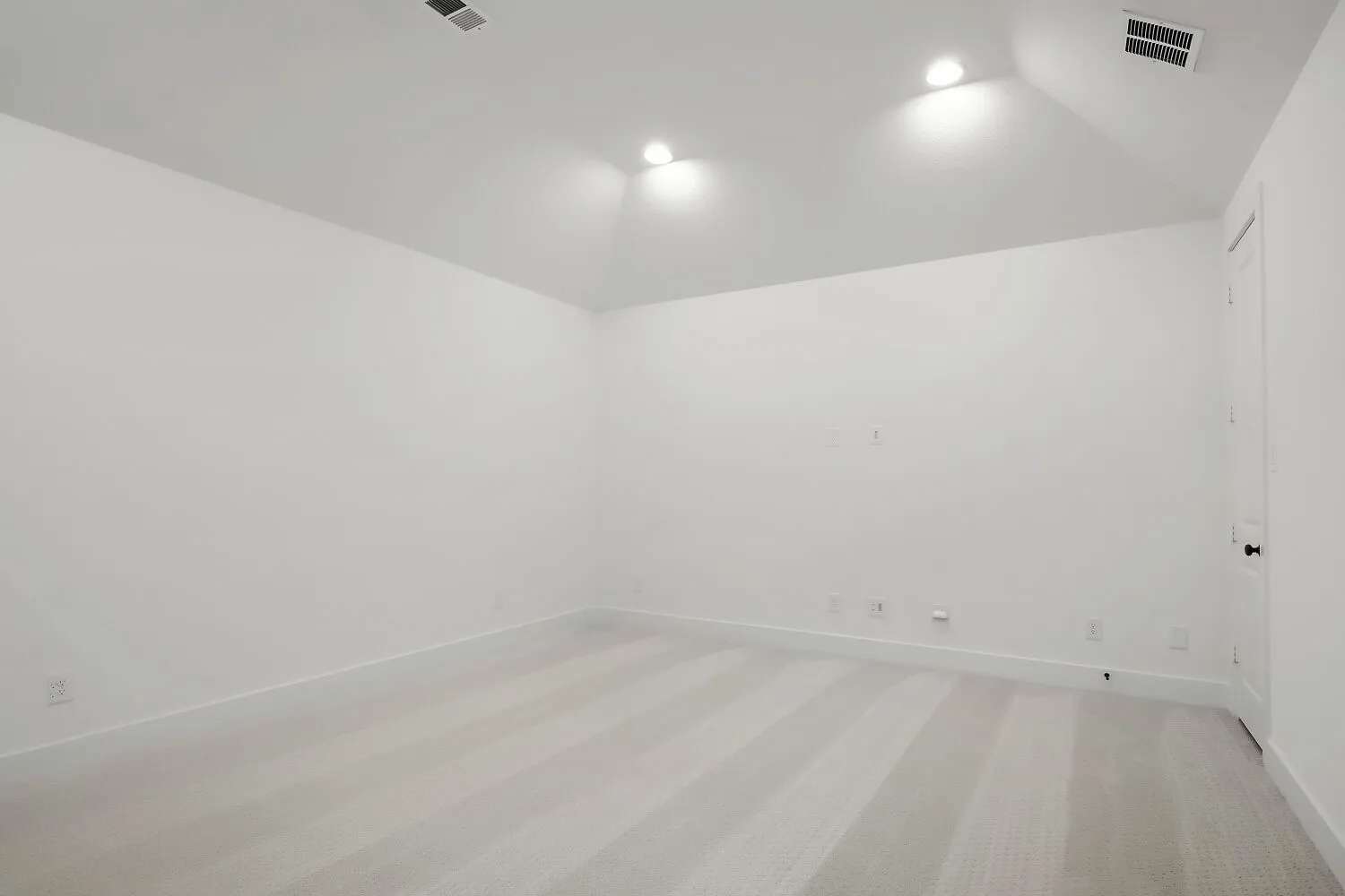 Carpeted room featuring a white interior, vaulted ceiling, recessed lighting, white baseboards, and a white door with a black knob
