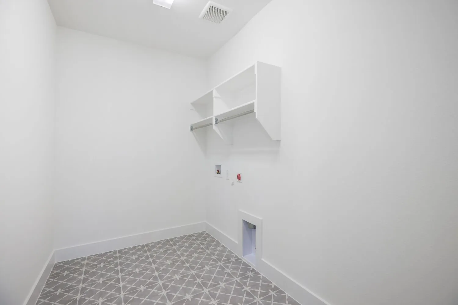 Laundry area featuring patterned floor tile, white walls, and built-in shelving with a hanging rod