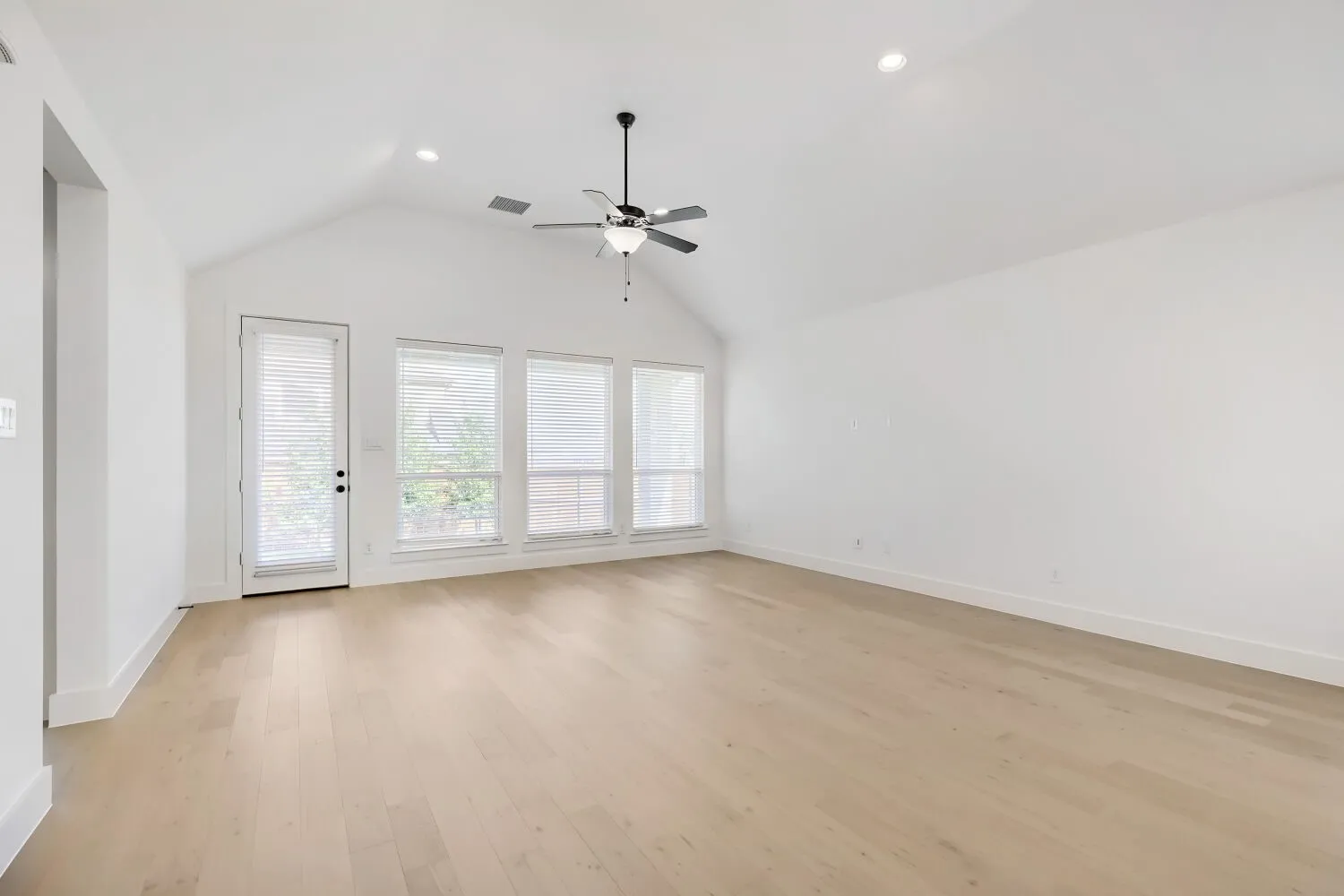 Spacious living area featuring a vaulted ceiling and wood-finish flooring
